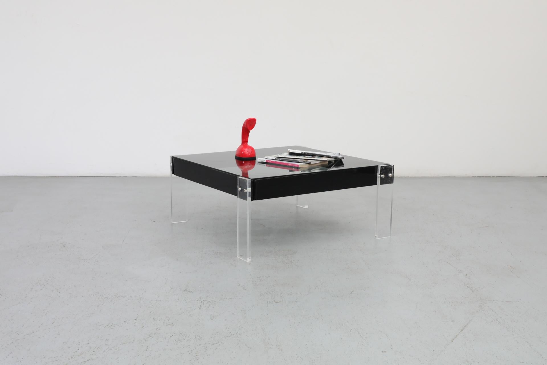Quadratischer Couchtisch mit dicken Beinen aus klarem Lucite und einer Platte aus Rauchglas von Roche Bobois. Seit seiner Gründung im Jahr 1950 hat sich Roche Bobois zu einem bedeutenden Unternehmen im Möbeldesign entwickelt. Anfänglich inspiriert