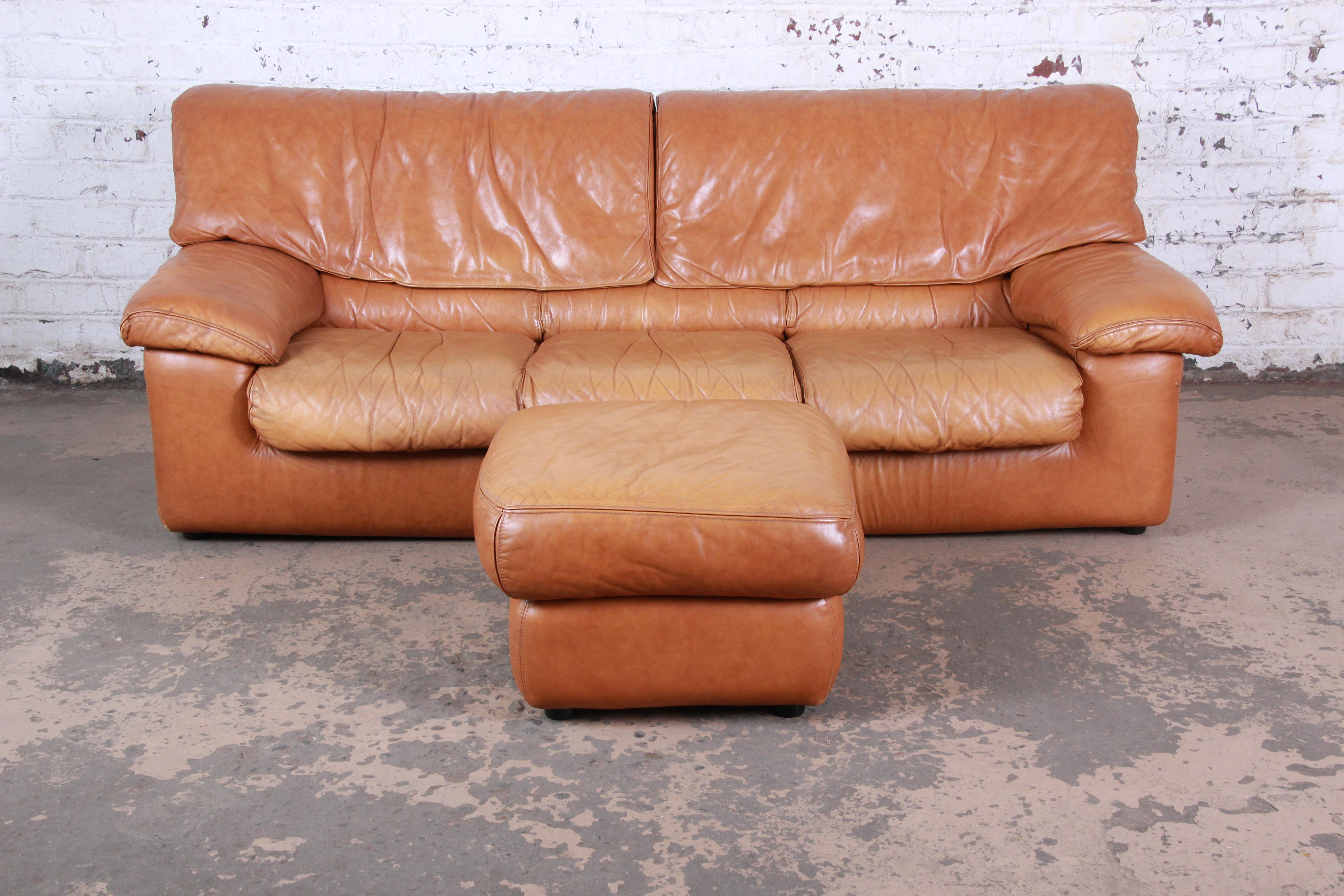 A gorgeous modern leather sofa and ottoman made in France by Roche Bobois, circa 1970s. The set features high grade camel colored brown leather with the perfect amount of wear and patina. The sofa is signed and in very good original vintage