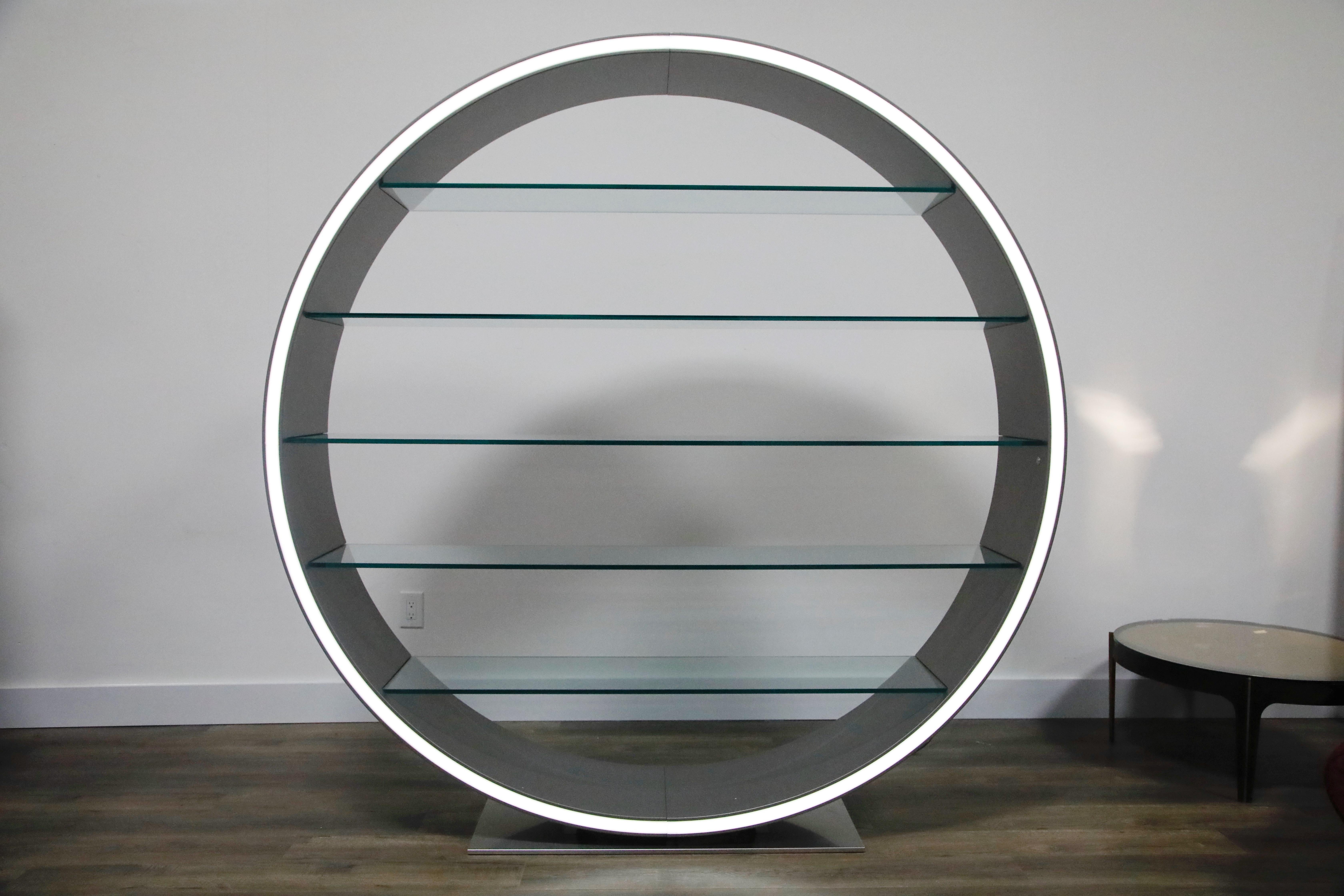 This phenomenal 'Omega' bookcase designed by Daniel Rode for Roche Bobois (Paris) features a design that is a perfect circle set on a steel base with five clear glass shelves that are both functional and structural. There is no back to this modern