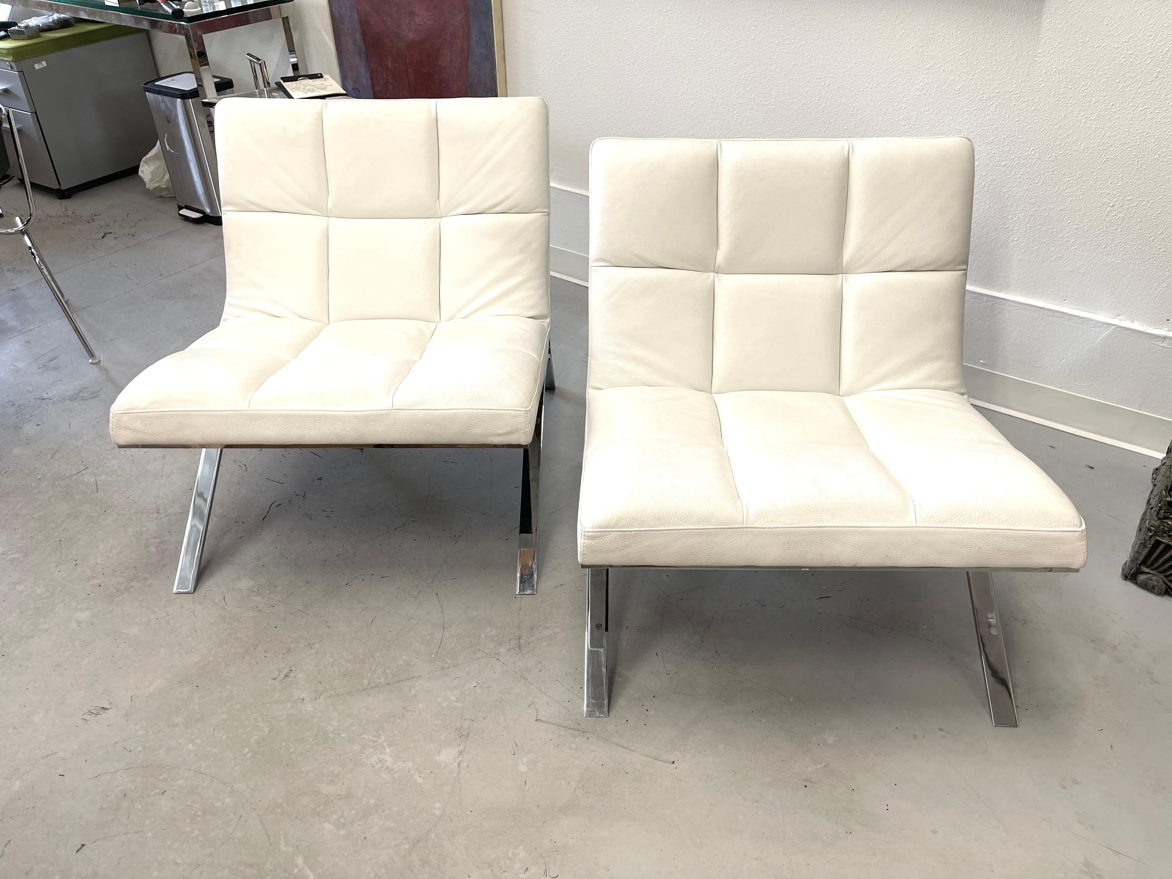A pair of Roche Bobois Skool chairs in white leather. Nice steel frame with an elegant form. The steel is in good condition, while the leather has a bit of minor wear to the very edges. Some slight darkening of the white leather. Pictured next to an