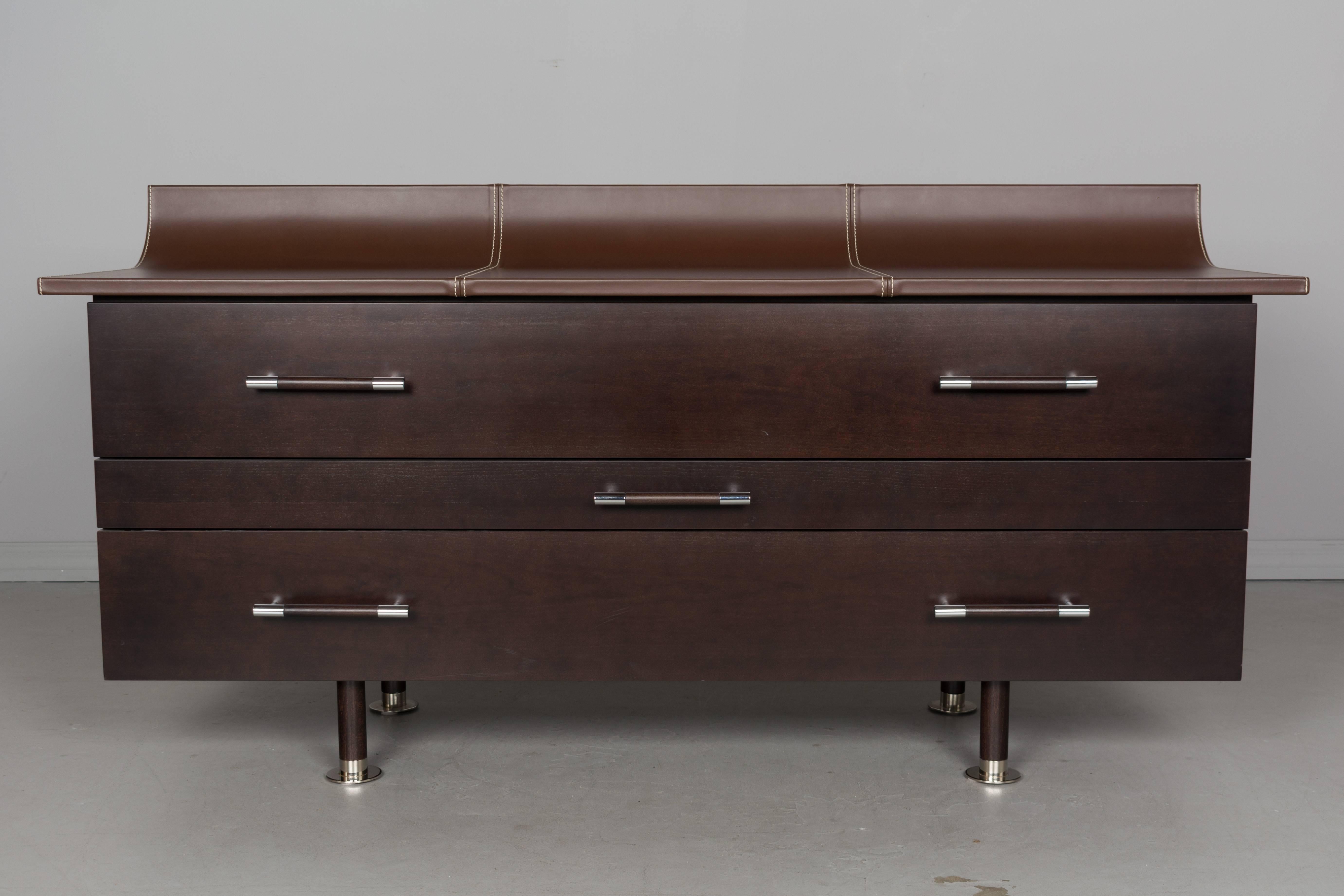 A contemporary dresser from the vanity bedroom collection for Roche Bobois by Milanese designer-architect Luigi Gorgoni. This three-drawer chest is made of cherry wood veneer with a top upholstered in split leather with contrasting stitching.