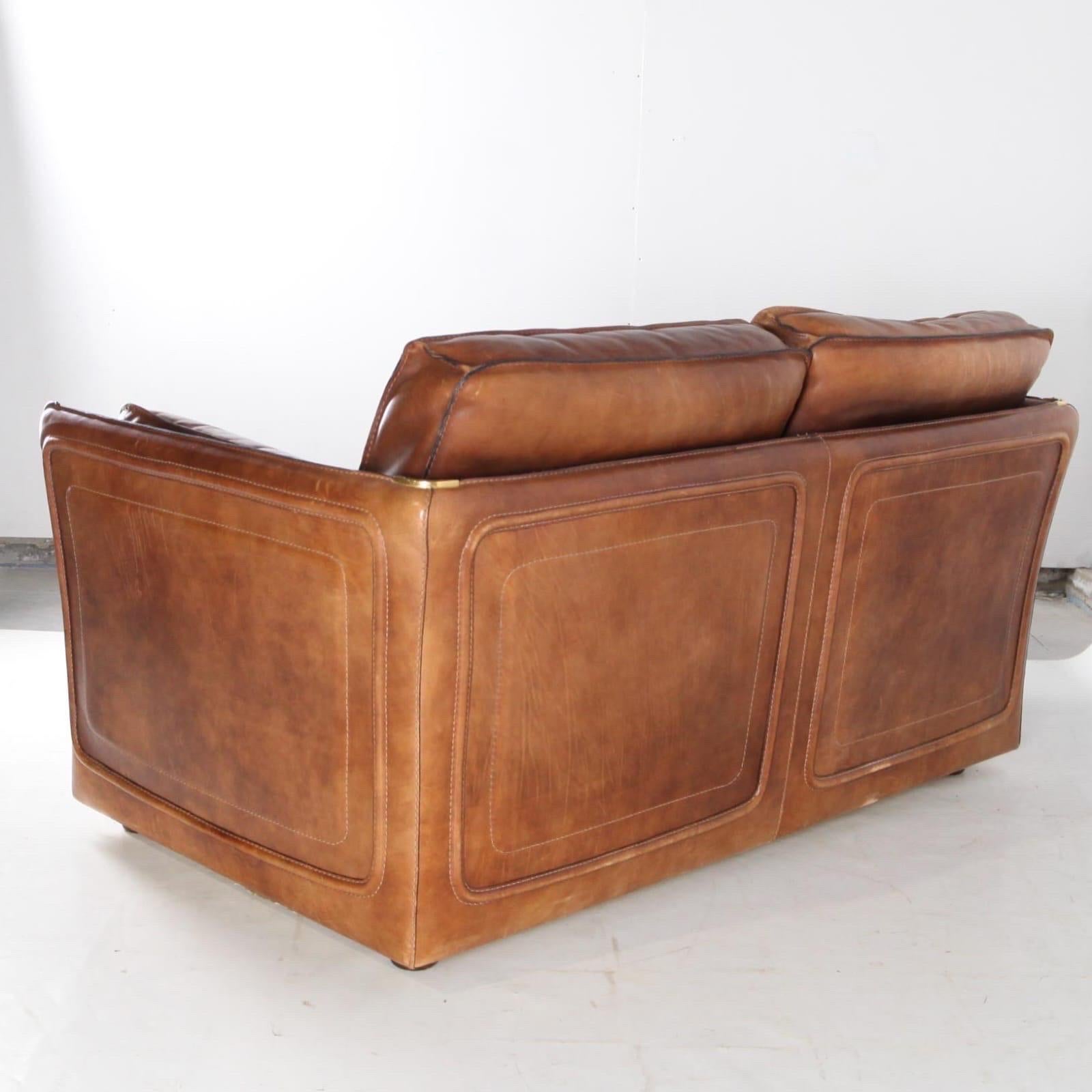 Beautiful Roche Bobois loveseat (2 seaters) from the seventies.
Thick buffalo leather, wooden legs, brass corners, very good condition. 
Comfortable, very good condition and beautiful patina.
Corresponding 3 seaters available too on this site. 
Pair