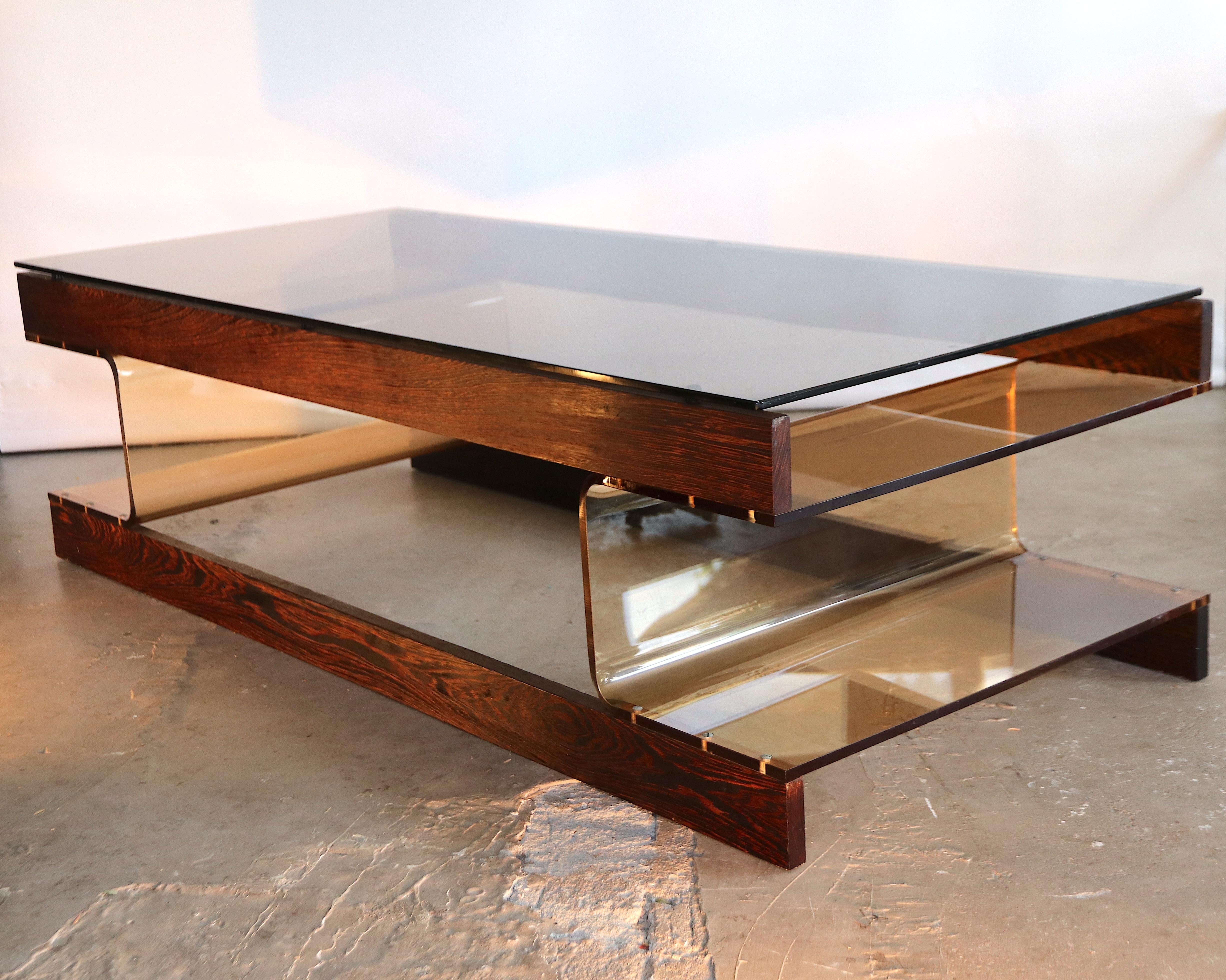 Beautiful Space Age coffee table by Roche Bobois with a tanned perspex base and a bronze smoked glass top. The support of the table can be used as magazine holder as well. This table is from the same line as the other Roche Bobois coffee table