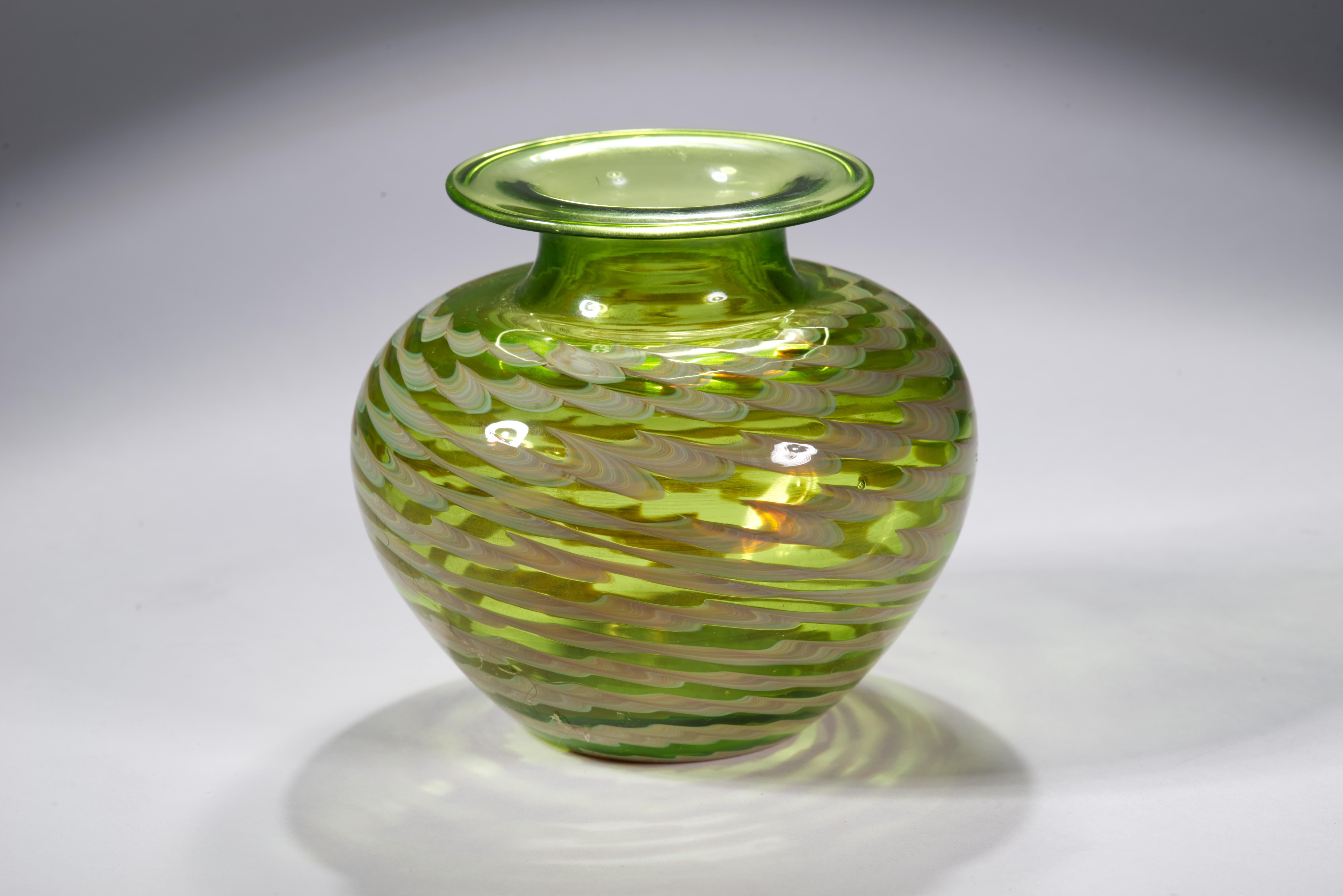 Il vaso vintage del primo Americal Studio Glass Movement presenta un complesso disegno astratto, con bande di vetro bianco sporco e verde chiaro che circondano il corpo del vaso; il vetro colorato fuso spicca sullo sfondo verde trasparente, guidando