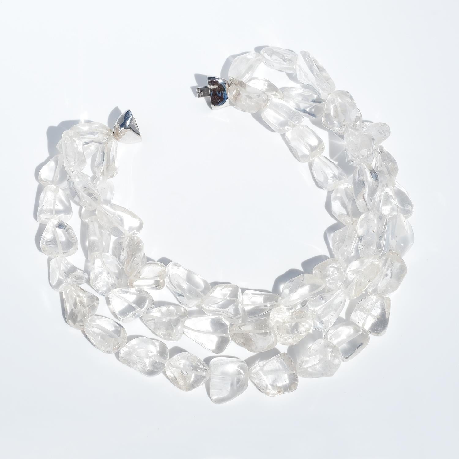 Collana girocollo vintage realizzata in cristallo di rocca naturale in tre fili. Ogni filo presenta pepite di cristallo irregolari e lucidate con forme organiche e traslucide. La collana si chiude intorno al collo, formando una presenza audace e