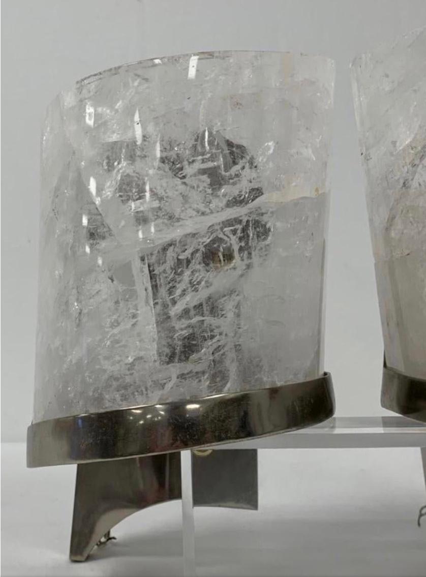 Elegant 0ne of a kind pair of modern hand carved and polished natural rock crystal wall sconces with chrome finished frames. Rock crystal is a semi-precious stone mined from the earth. The chrome frames along with the rock crystal give these a