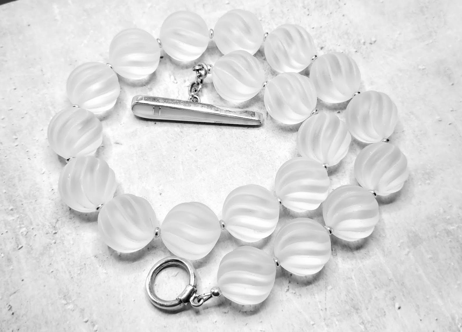 Genuine Swirl Carved Frosted Rock Crystal Beaded Necklace with Beautiful Mother of Pearl Toggle Clasp

The length of the necklace is 17 inches (43 cm). The size of the swirl carved beads is 18 mm.
The beads are like frozen smooth ice on a river.
In