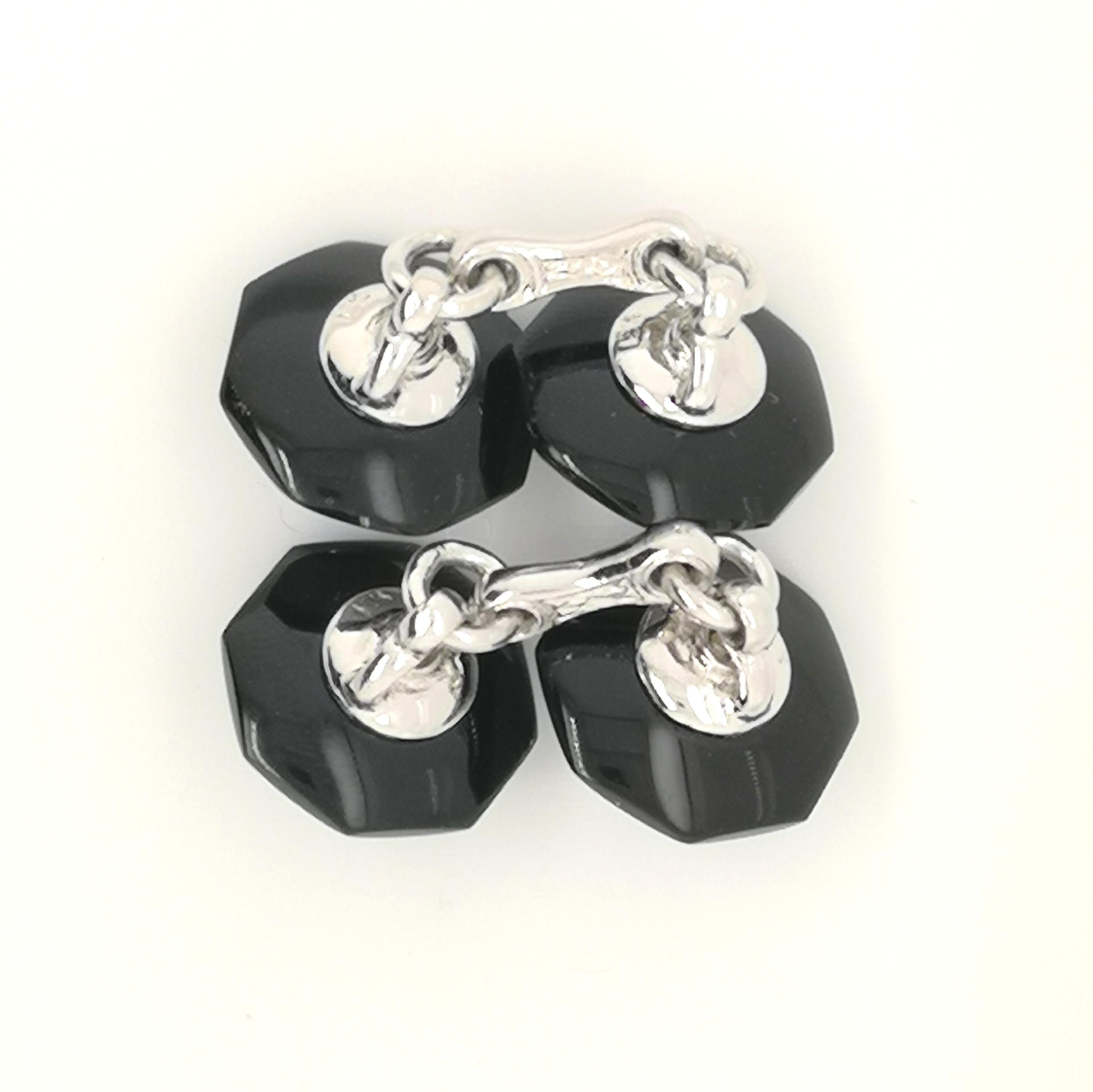 A modern pair of black onyx, rock crystal and diamond cufflinks, with a round brilliant-cut diamond set in the centre of carved rock crystal, with a hexagonal border of black onyx, mounted in white gold.