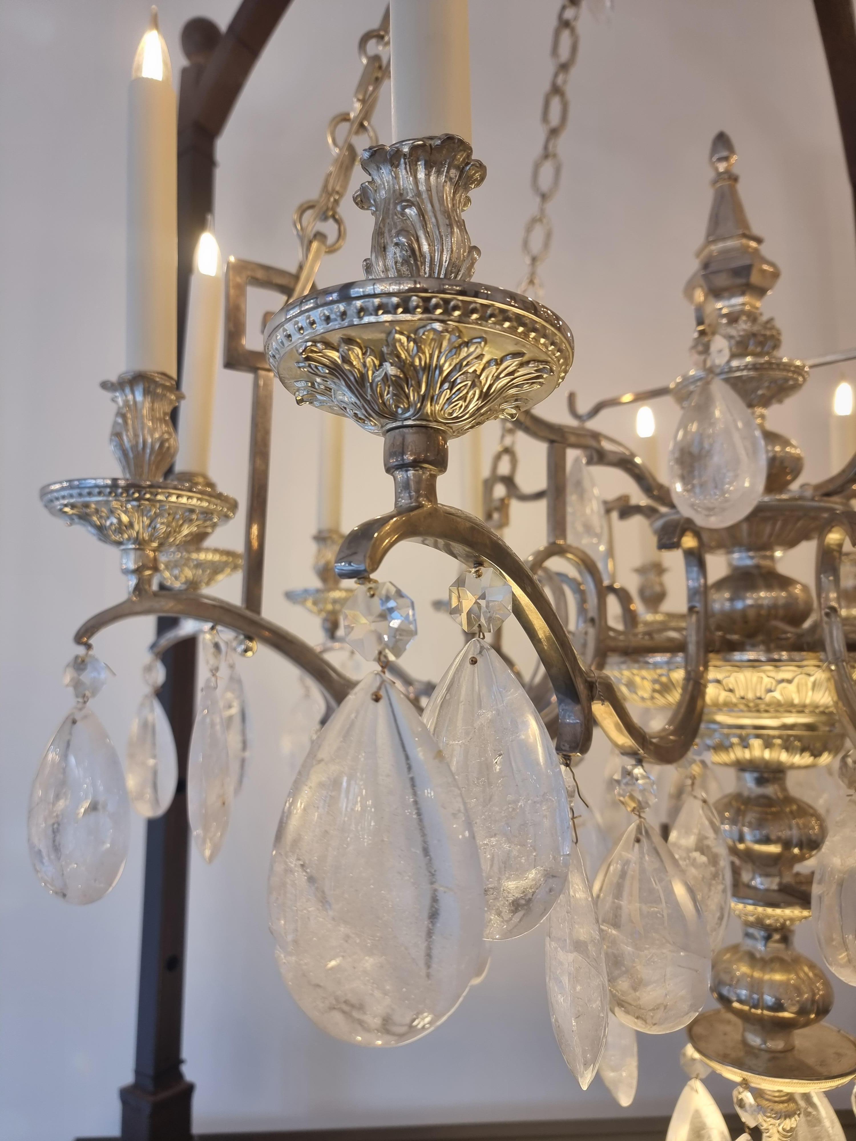 Ce lustre est une variation originale des modèles à chaîne que l'on pouvait trouver au XVIIIe siècle, comme le lustre torchère d'époque Louis XVI du Château de Versailles.
Sur une coupe centrale ajourée, surmontée d'une dague métallique, se