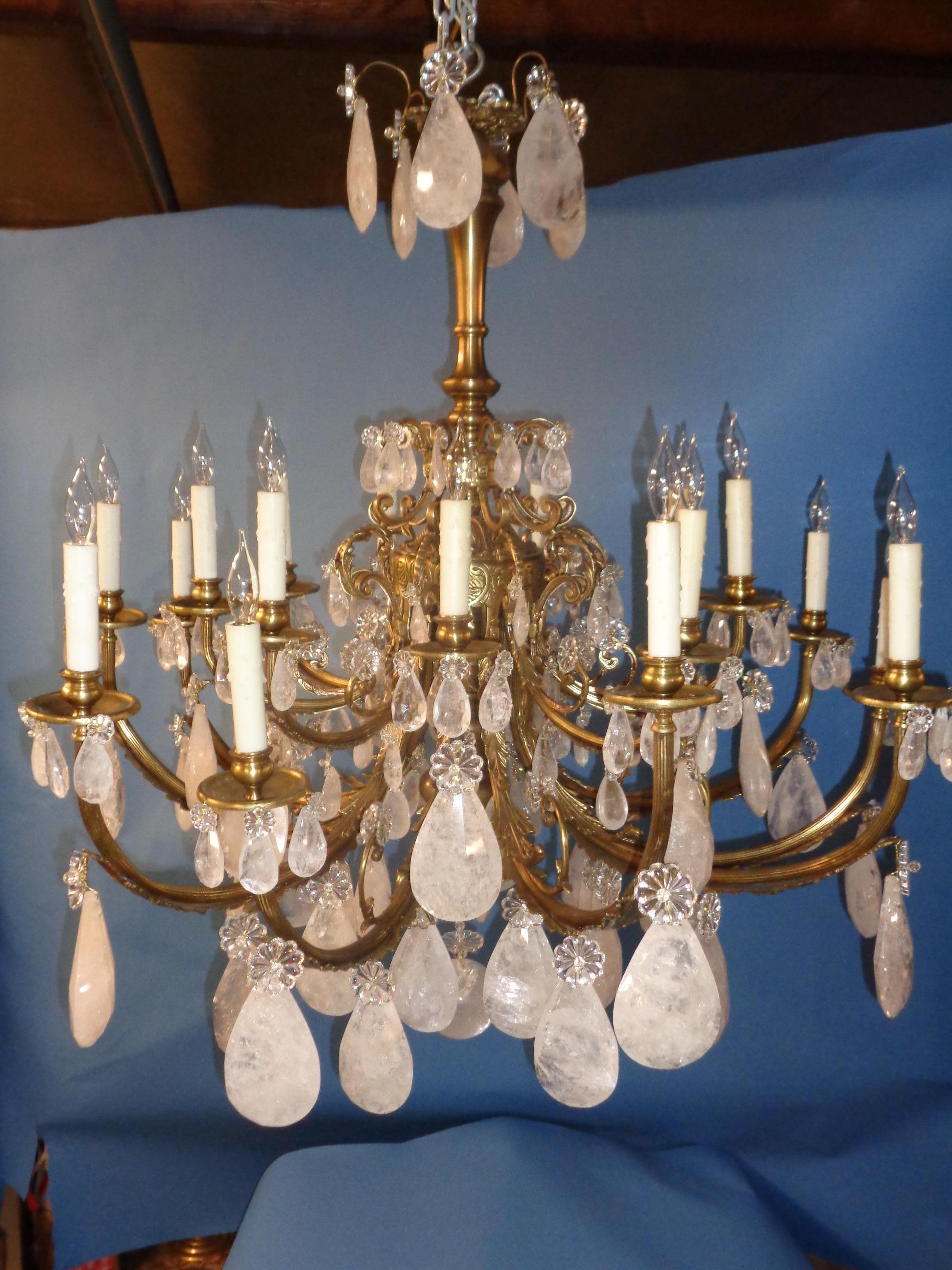 French Louis XV style rock crystal chandelier. The frame is patinated silver over bronze. The crystals are faceted tear drop shaped. There are eighteen candlelights around the perimeter. It has been newly electrified.