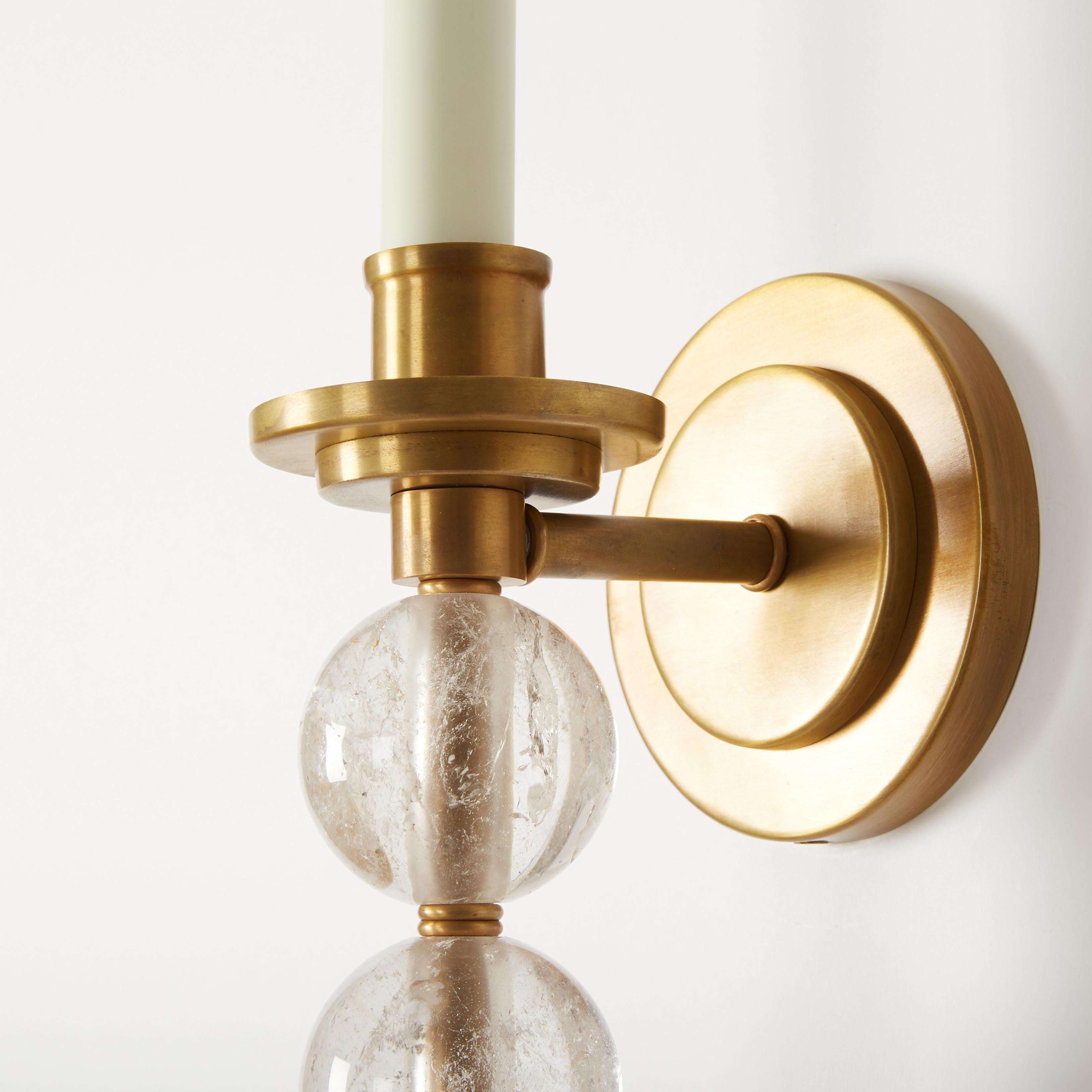 A pair of custom single-light Ephorus sconces with a satin brass finish and three graduated, hand carved rock crystal balls. These Transitional sconces are sold as a pair but can also be purchased individually. Each sconce has a medium Edison