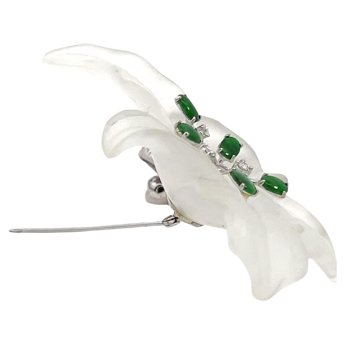 Large rock crystal flower brooch with a diamond pave stem. The flower resembles a single orchid with diamond and green gemstone pistols set in 18 karat white gold. 
Adorn yourself with this enchanting statement piece and let your style bloom with