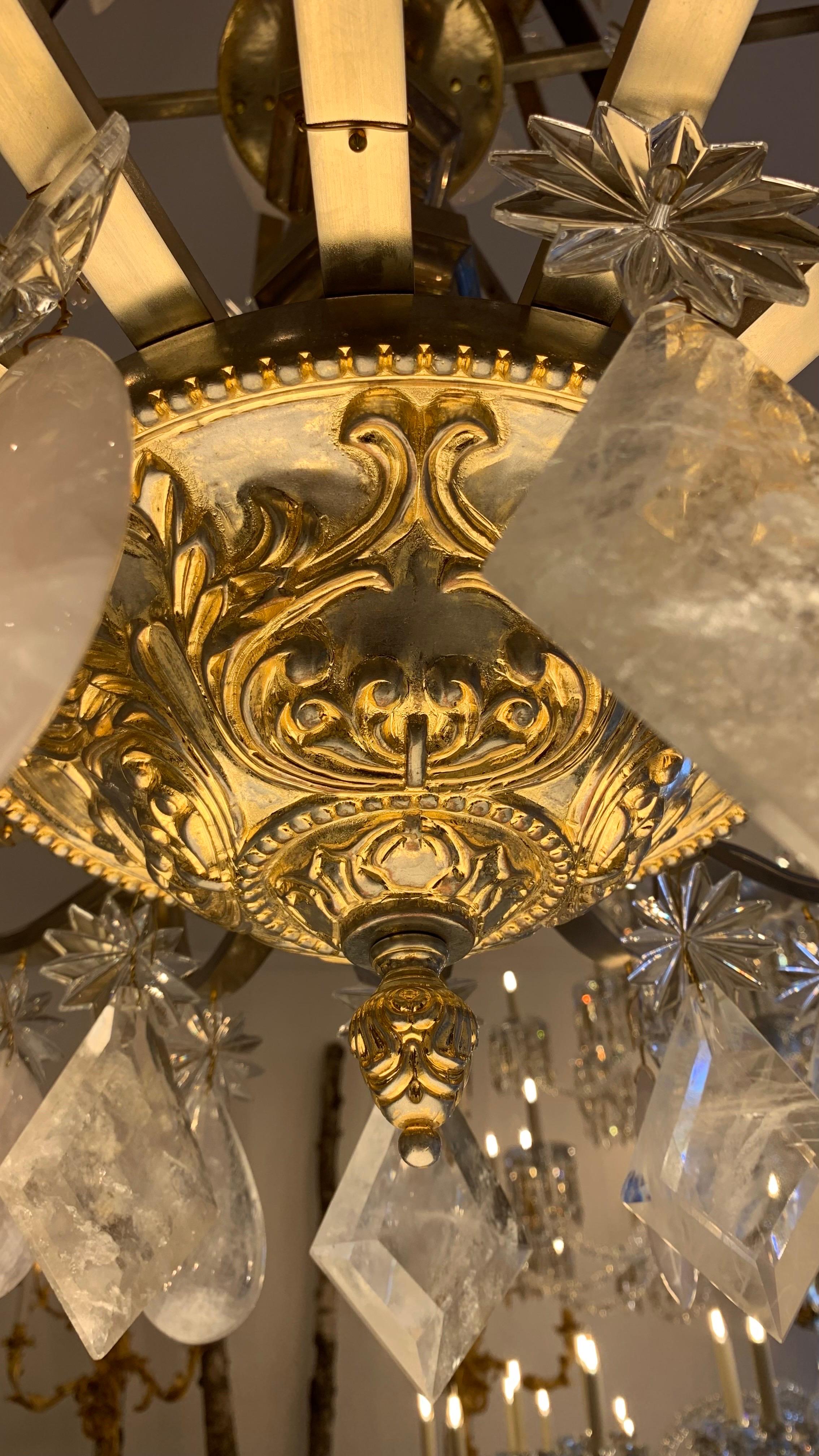 This chandelier in the shape of a lyre is composed of a central shaft made of bronze rhombuses.

The base of the shaft, punctuated by a gable, gives rise to 18 curved arms of light distributed in a circle and decorated with white and pink rock