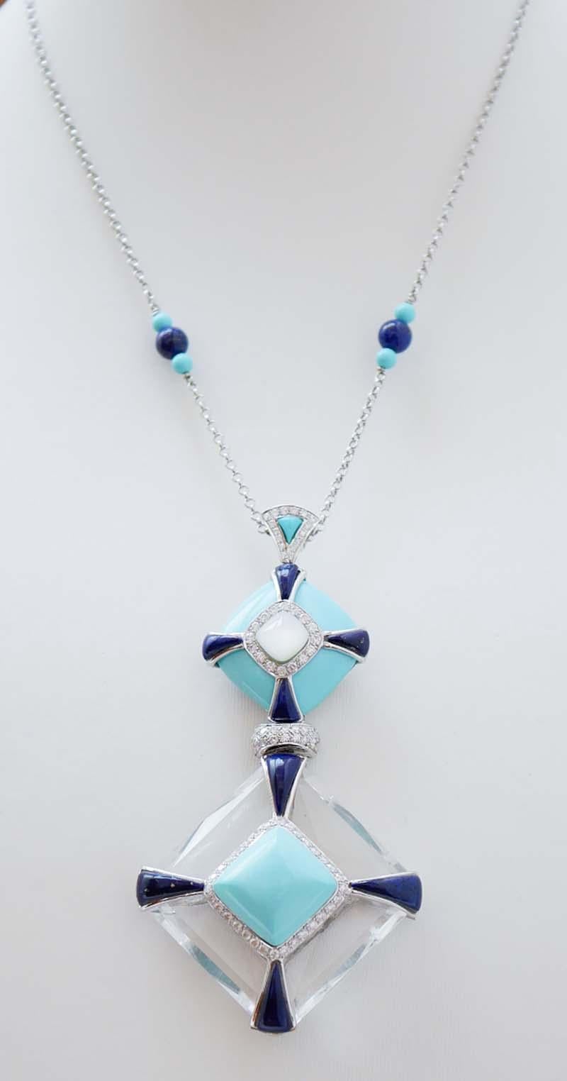 Incredibile collana con ciondolo in oro bianco 18 kt con turchese, diamanti, lapis e pietre bianche nella parte superiore; sotto, un cristallo di rocca con turchese centrale circondato da diamanti e, lateralmente, lapis. Lungo la catena, due sfere