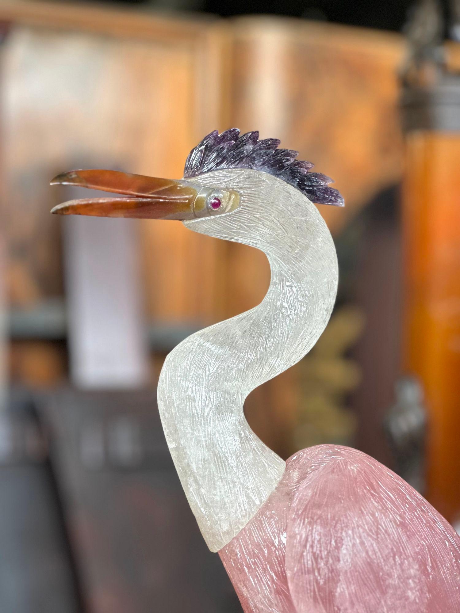 Heron bird sculpture made with rock crystal, rose quartz, agate, amethyst and metal limbs. Stands on a gorgeous amethyst base with flower details made of tiger's eye petals.