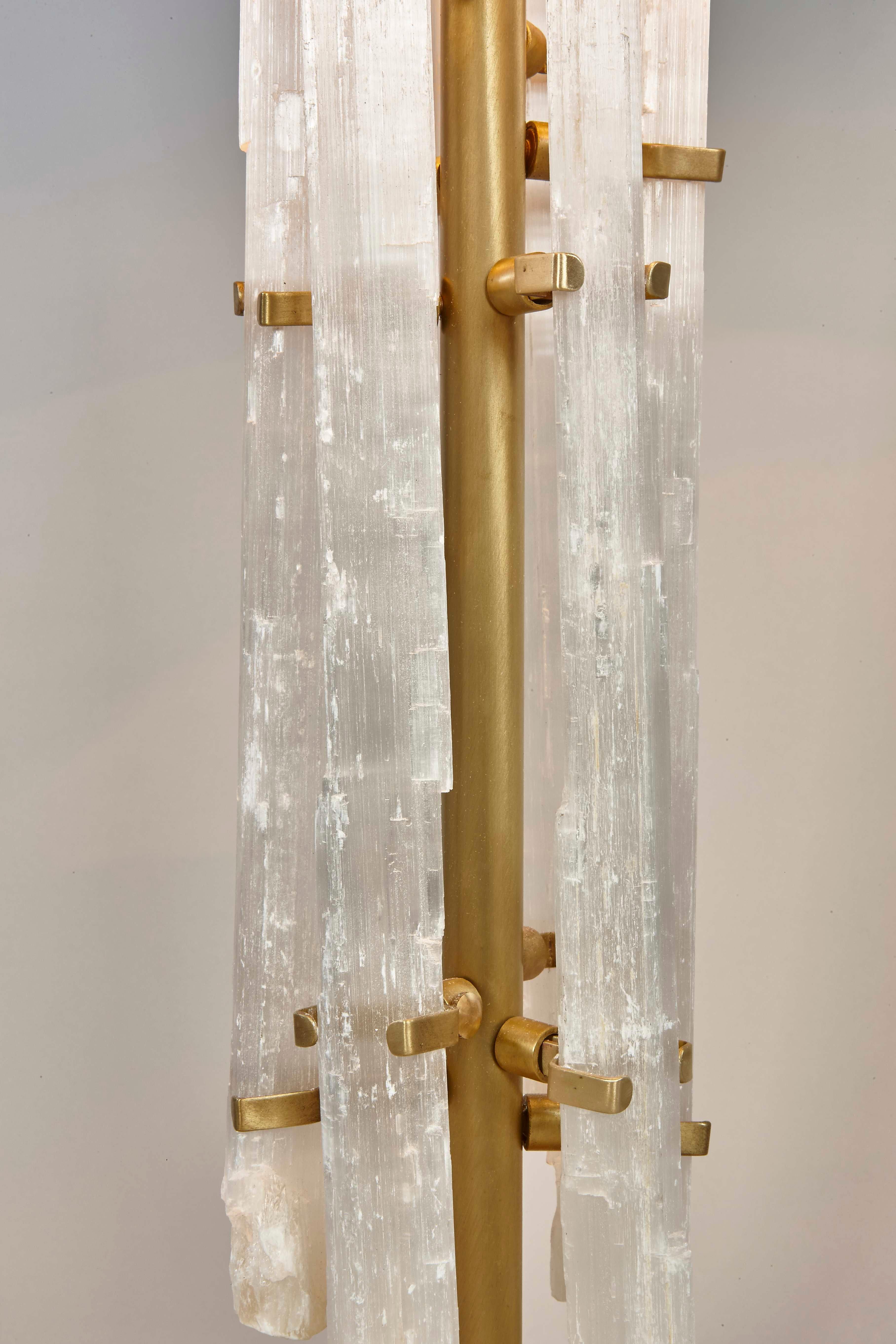 Notre lampe de table en cristal de roche est minutieusement fabriquée à la main, à l'aide de délicates tiges de cristal de roche positionnées organiquement autour d'une tige en bronze. Cette magnifique lampe apporte à la fois élégance et