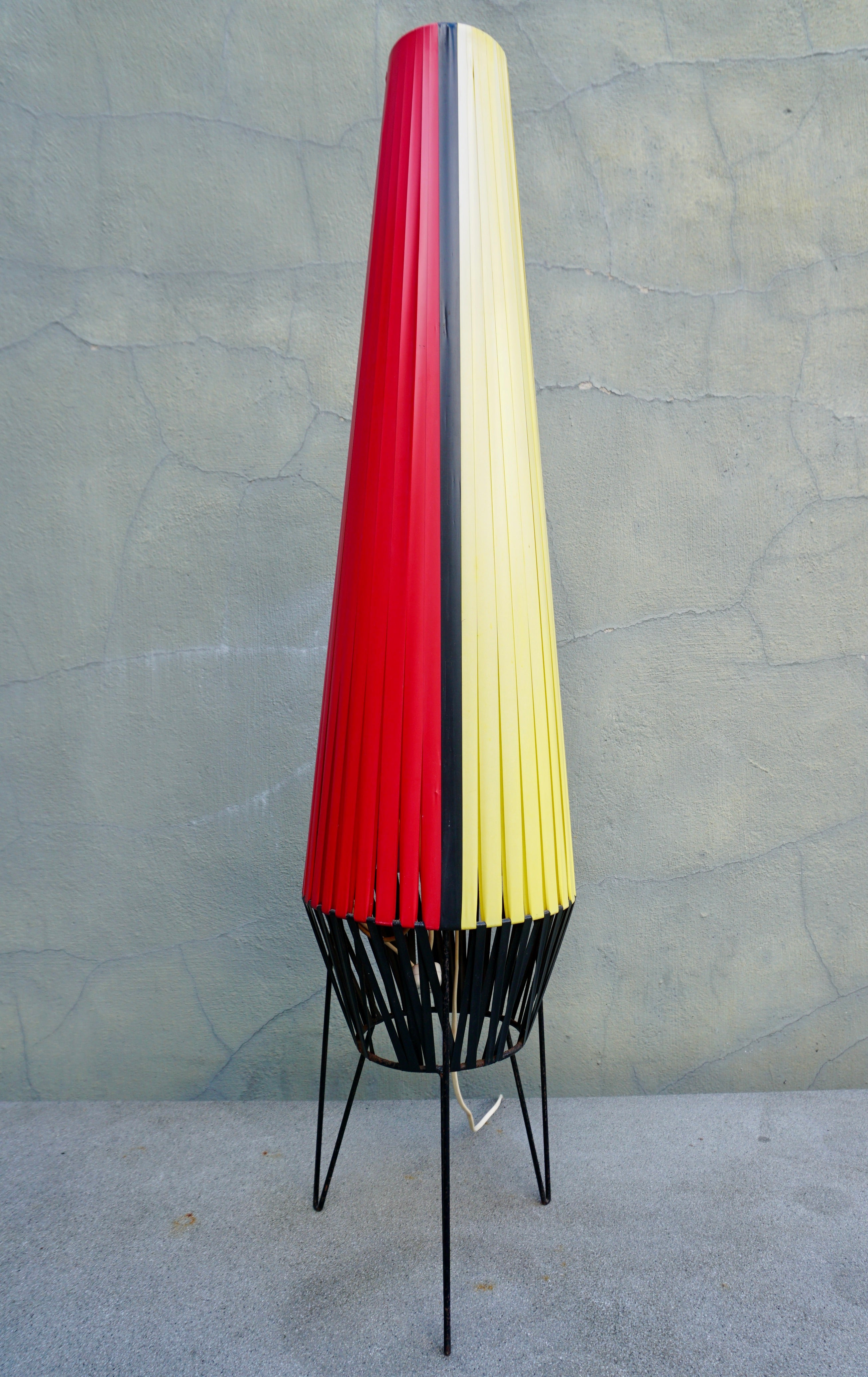 Rocket floor lamp with plastic straps in red, purple, yellow and black on a black metal tripod.

Height 41.3