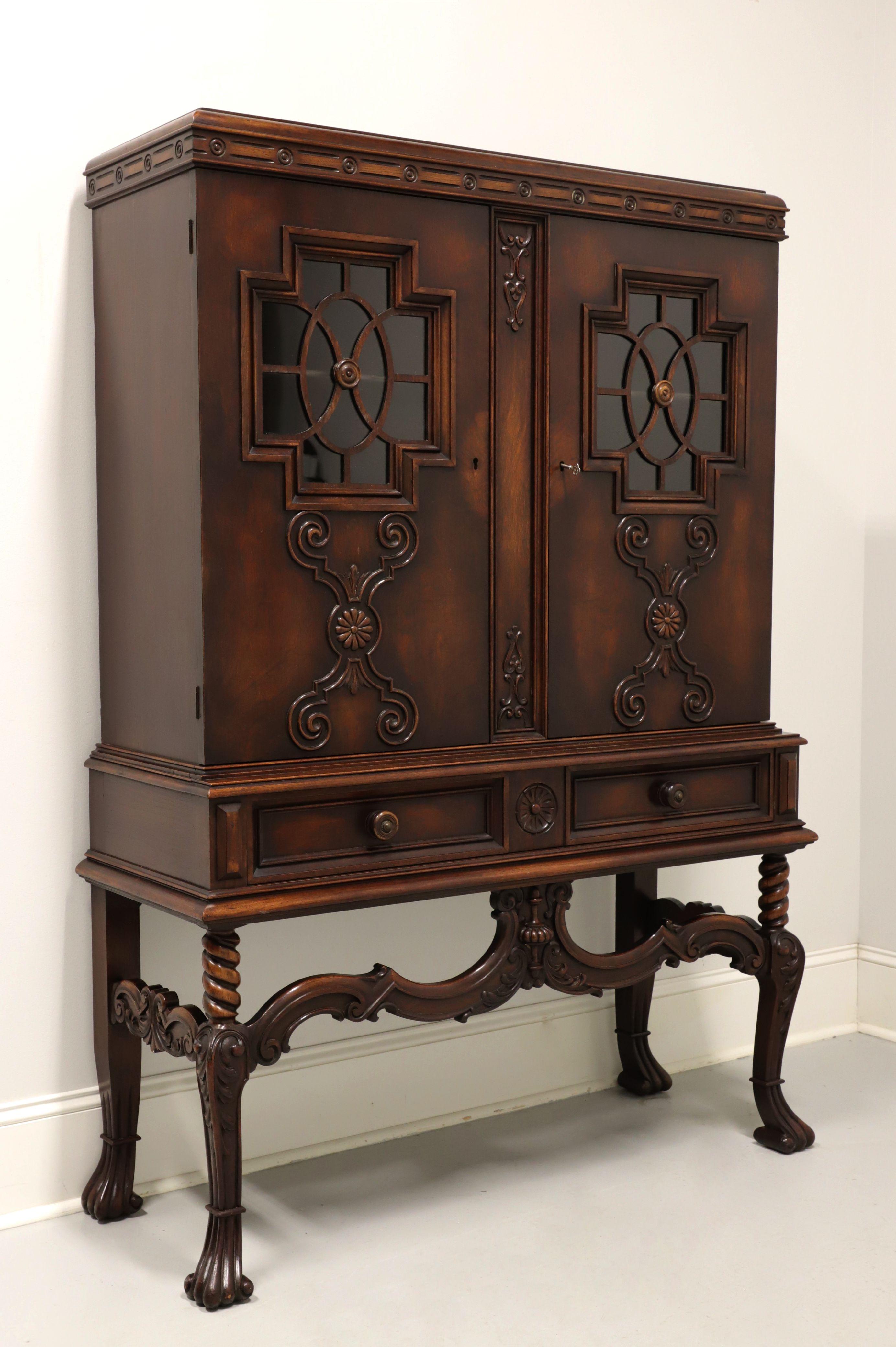 An antique French Gothic style china cabinet by Rockford Chair & Furniture Co. Walnut with decorative cornice to top, carved doors with cross like paned glass inserts, beveled edges to apron, recessed drawer fronts, decoratively carved stretchers &