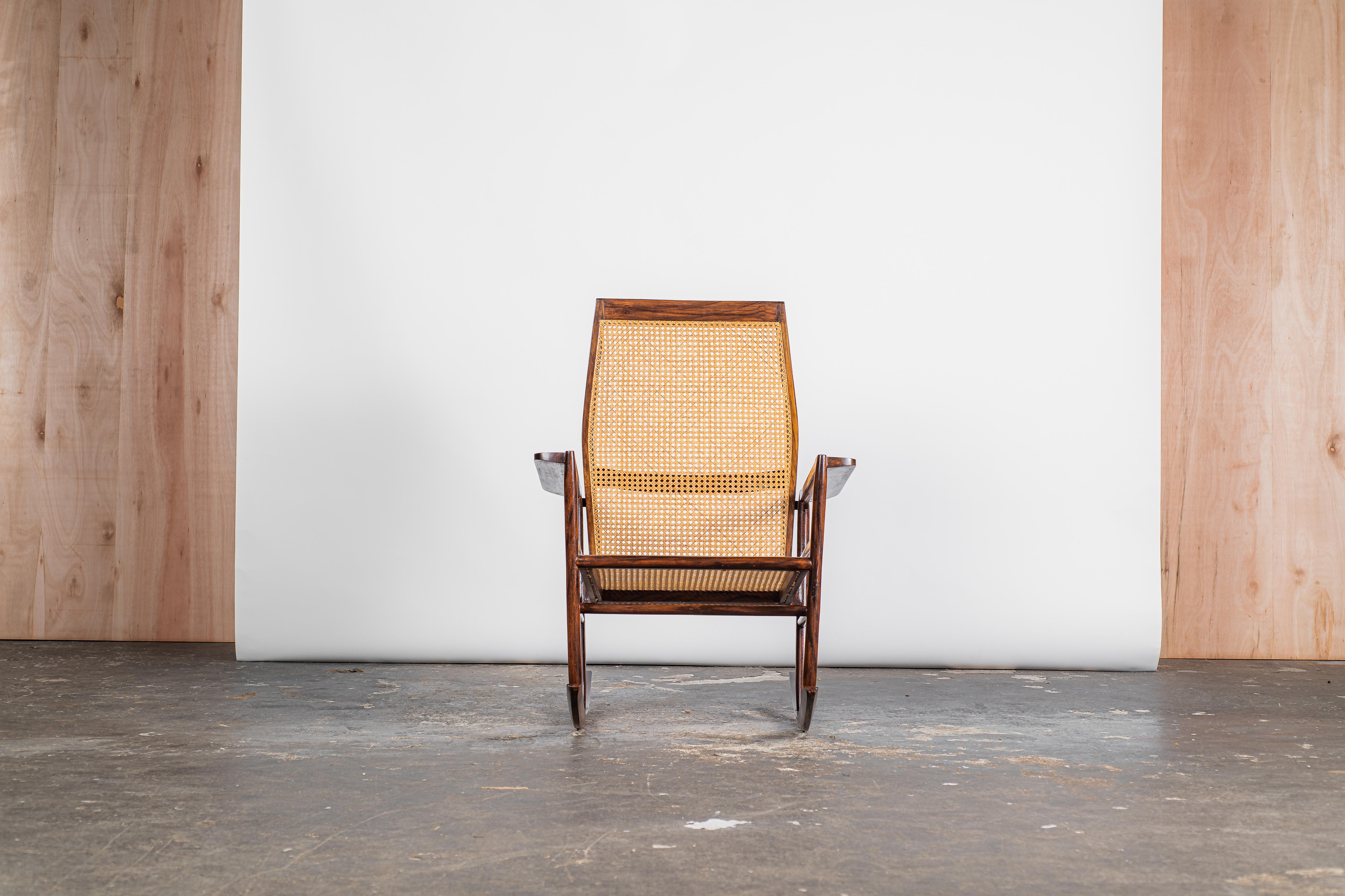 Dieser Schaukelstuhl aus dem Jahr 1947, der dem kreativen Genie von Joaquim Tenreiro entsprungen ist, verkörpert ein exquisites Zeugnis des Designs aus der Mitte des 20. Jahrhunderts. Das Gestell aus Hartholz, das elegant mit Sitz und Rückenlehne