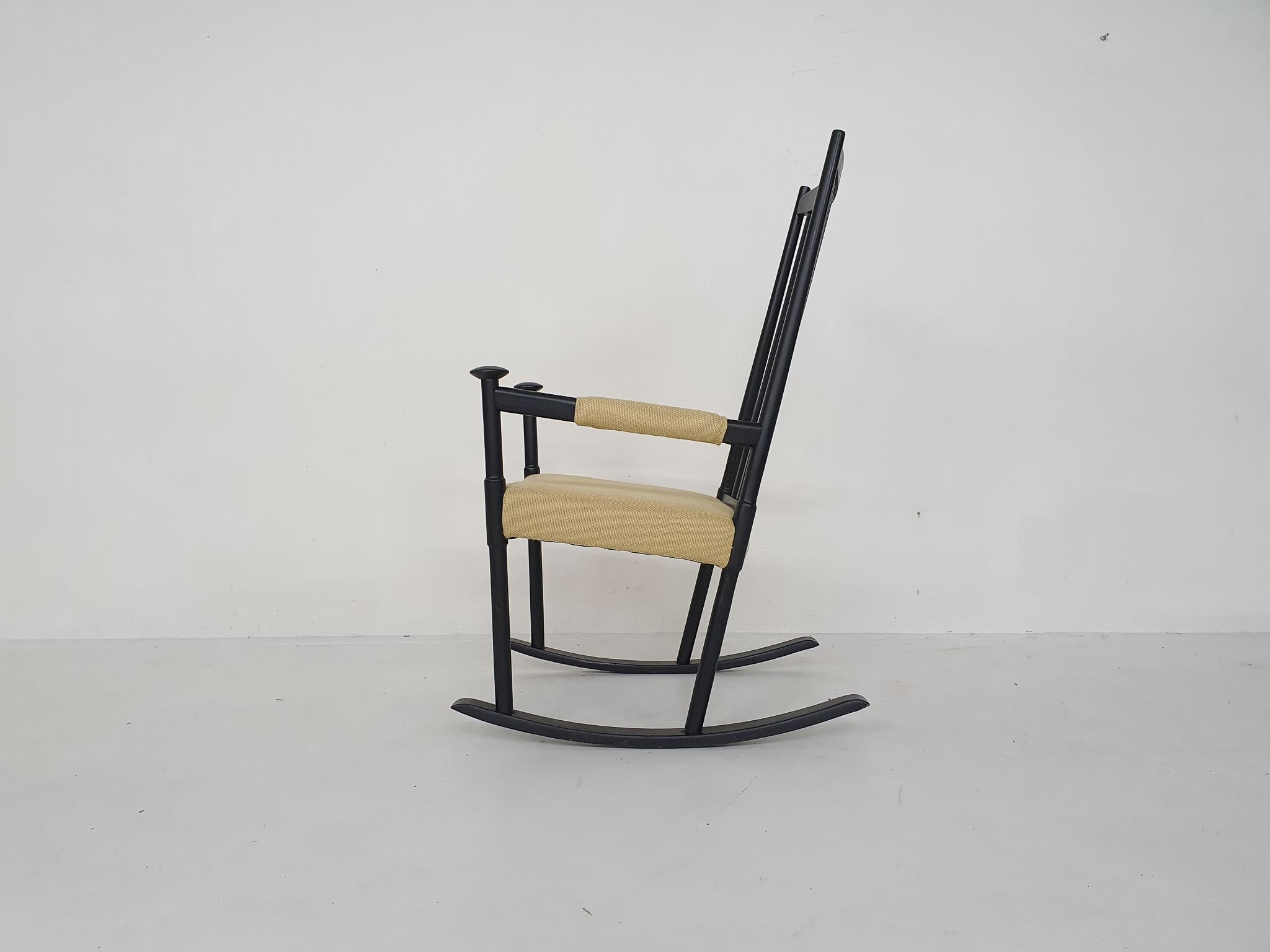 Black wooden rocking chair with new light yellow upholstery and new filling.