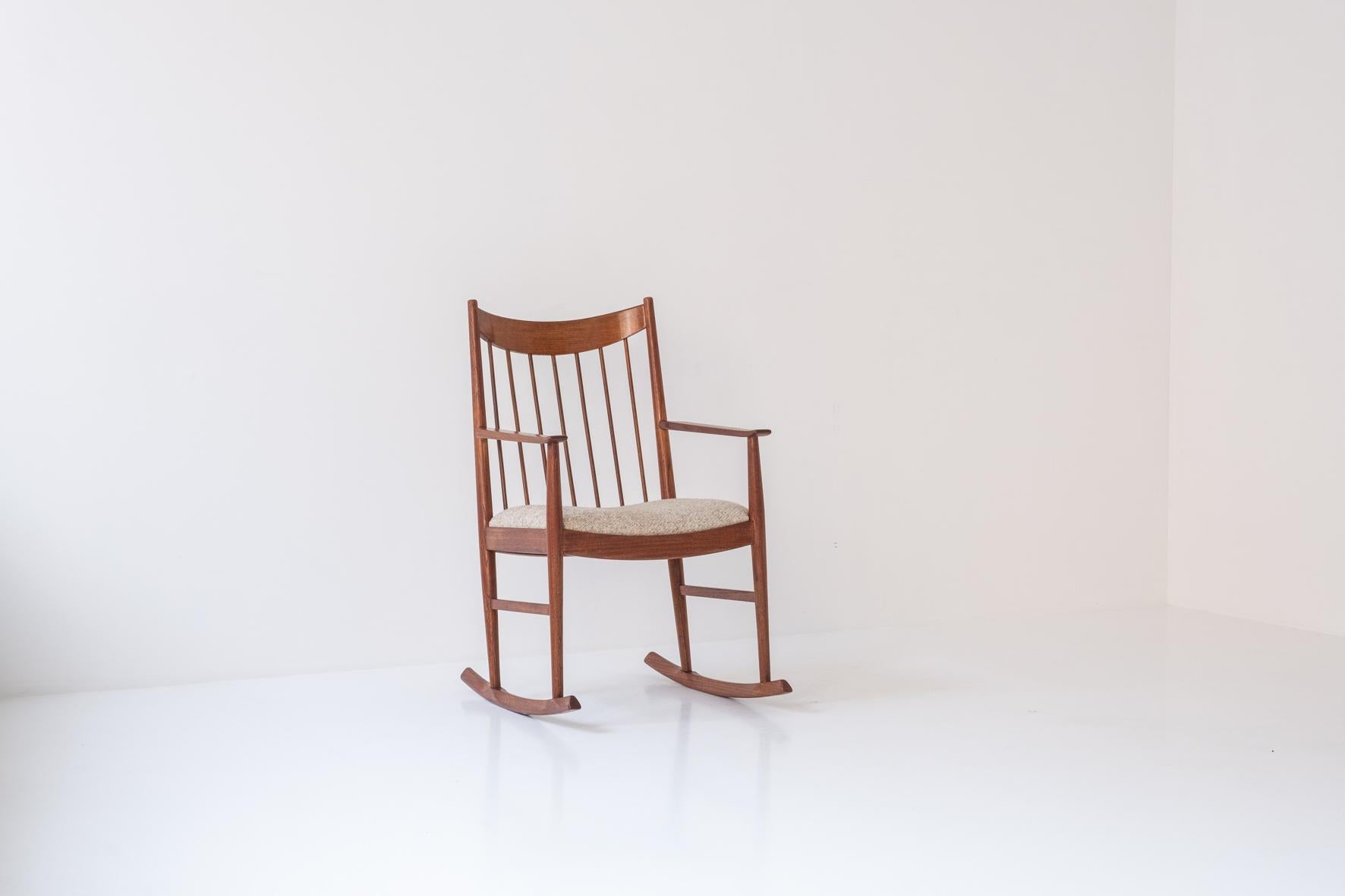Rocking chair designed by Arne Vodder for Sibast, Denmark 1960s. This chair is made out of teak and has a curved spindle back rest.  The seating is upholstered with a wool fabric upholstery. Restored with love. Labeled underneath.