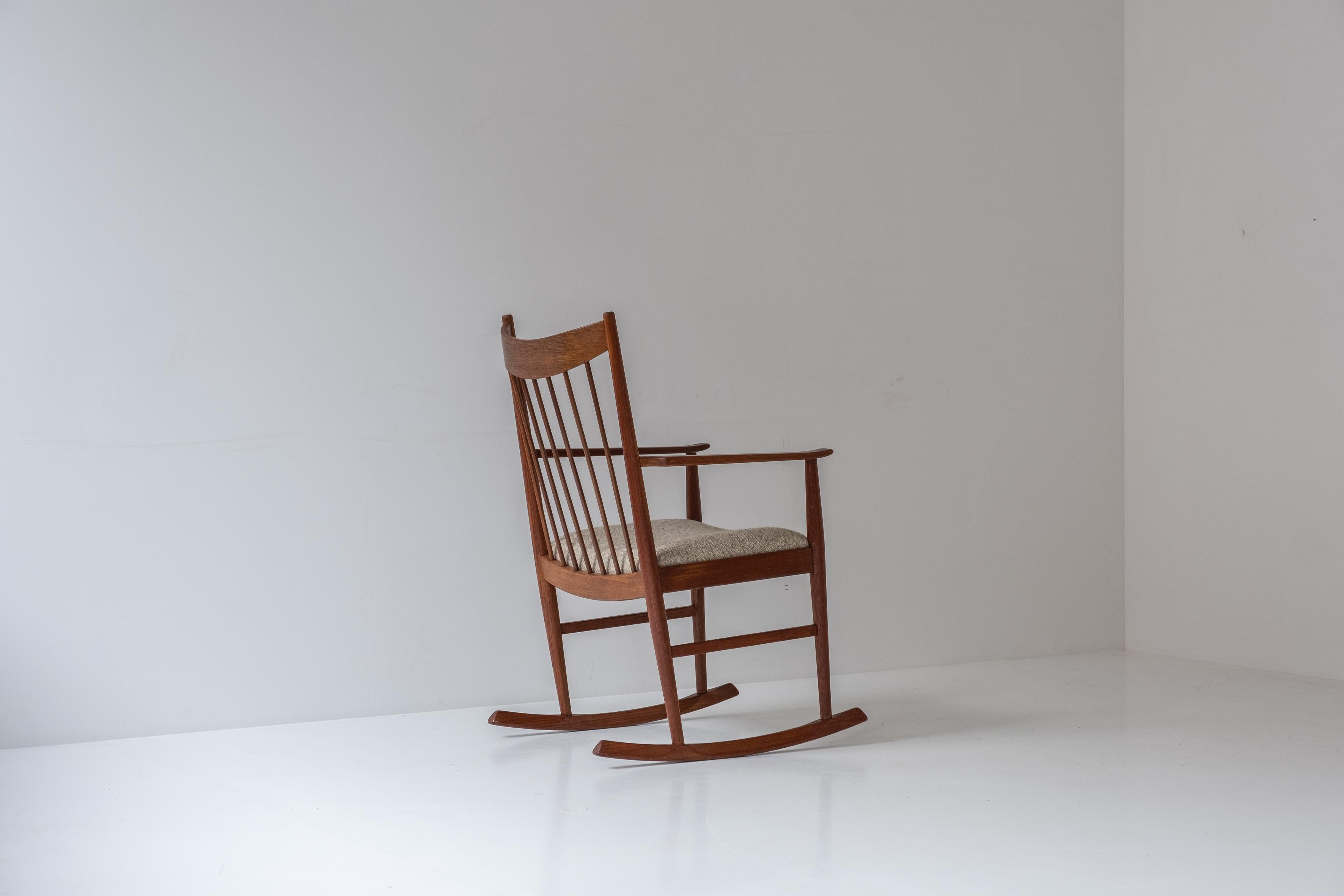 Rocking chair designed by Helge Sibast for Sibast, Denmark 1960s. This chair is made out of teak and has a curved spindle back rest.  The seating is upholstered with a wool fabric upholstery. Restored with love. Labeled underneath.