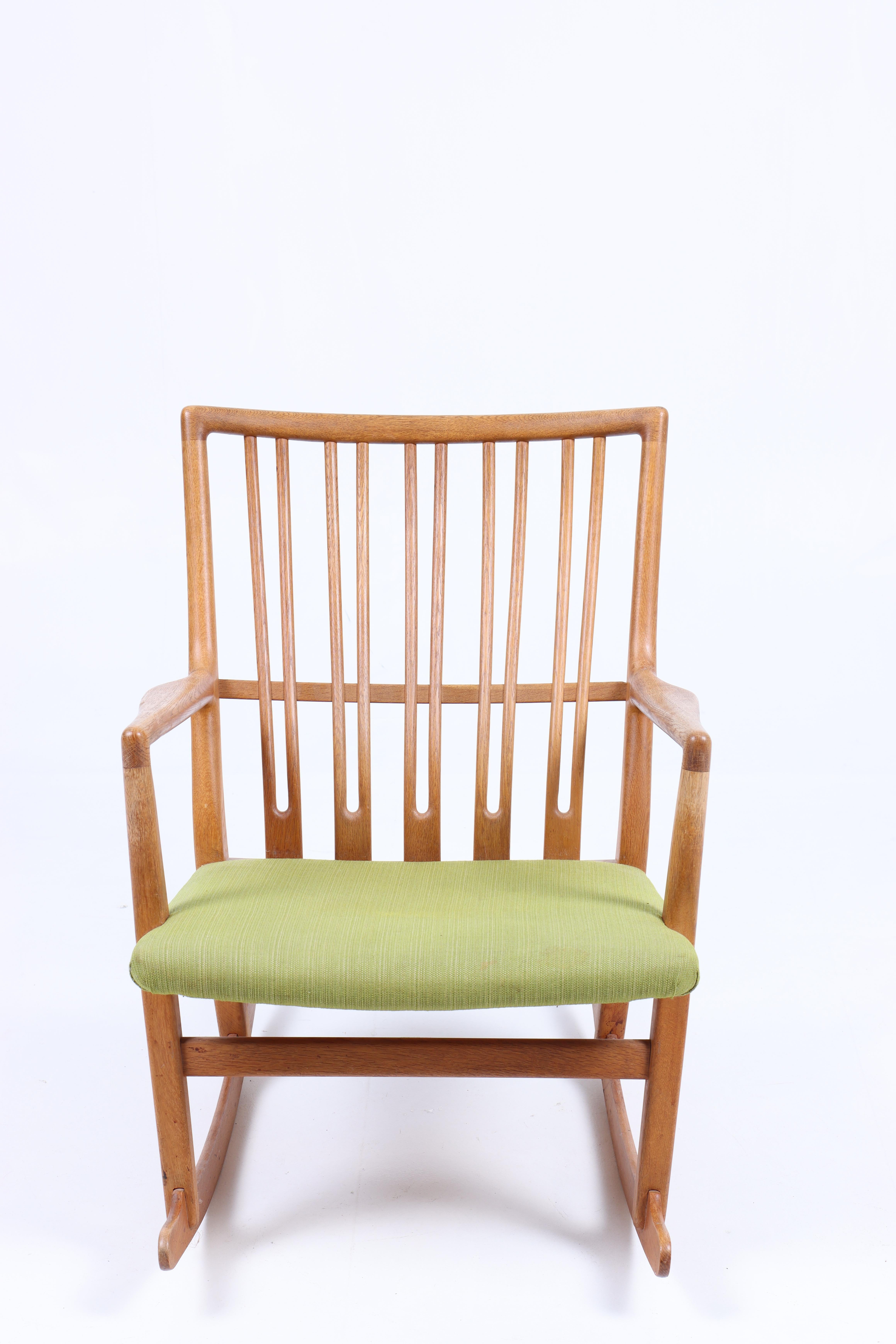 Chaise à bascule en chêne et tissu, conçue par Hans Wegner et fabriquée par Mikael Laursen. Excellent état.