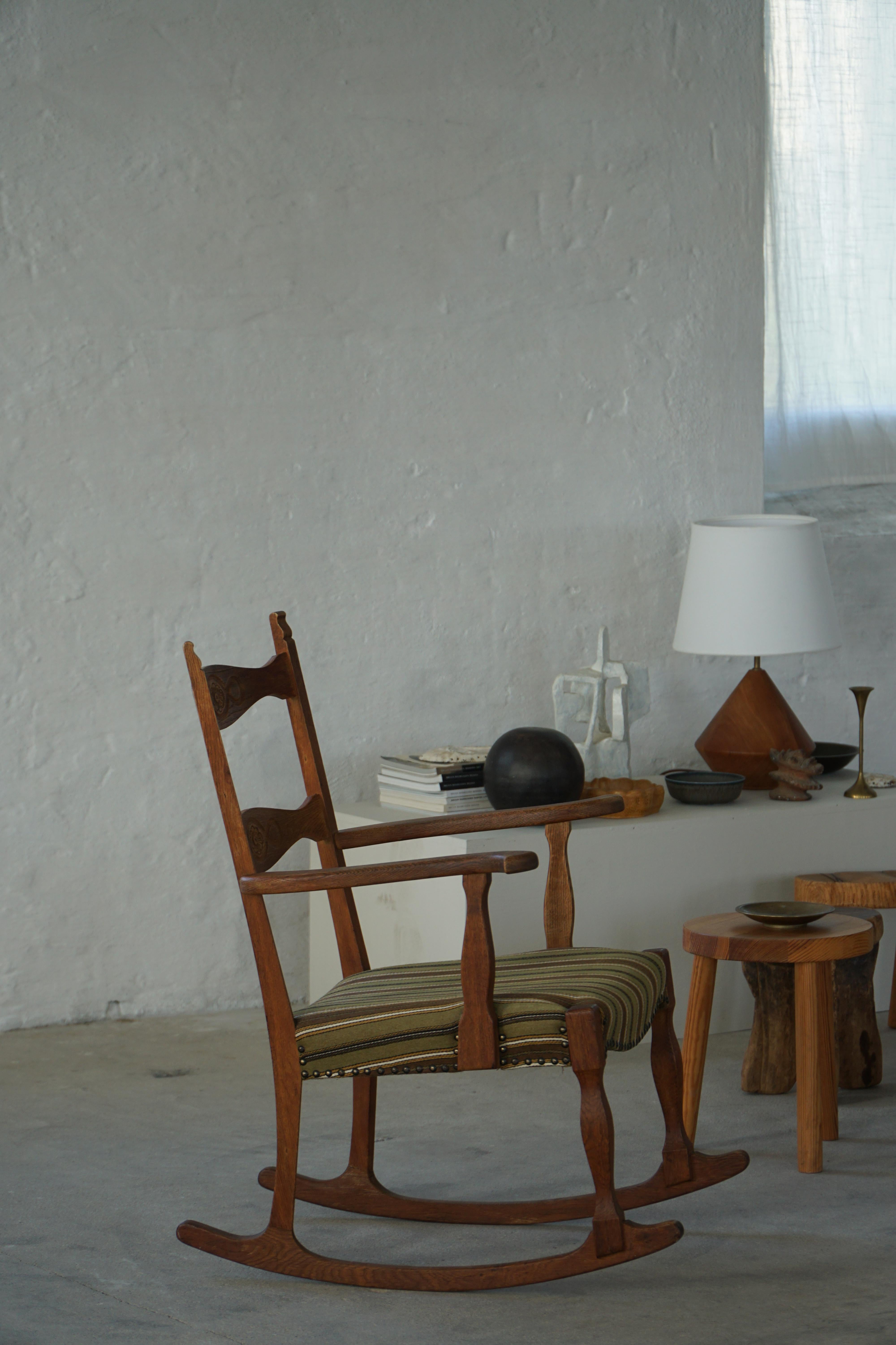 Magnifique fauteuil à bascule en chêne massif, dont l'assise a été retapissée dans un étonnant textile à rayures dans les tons vert, marron et jaune moutarde. Conçu par Henning (Henry) Kjærnulf pour E.G Møbelfabrik, Danemark, dans les années