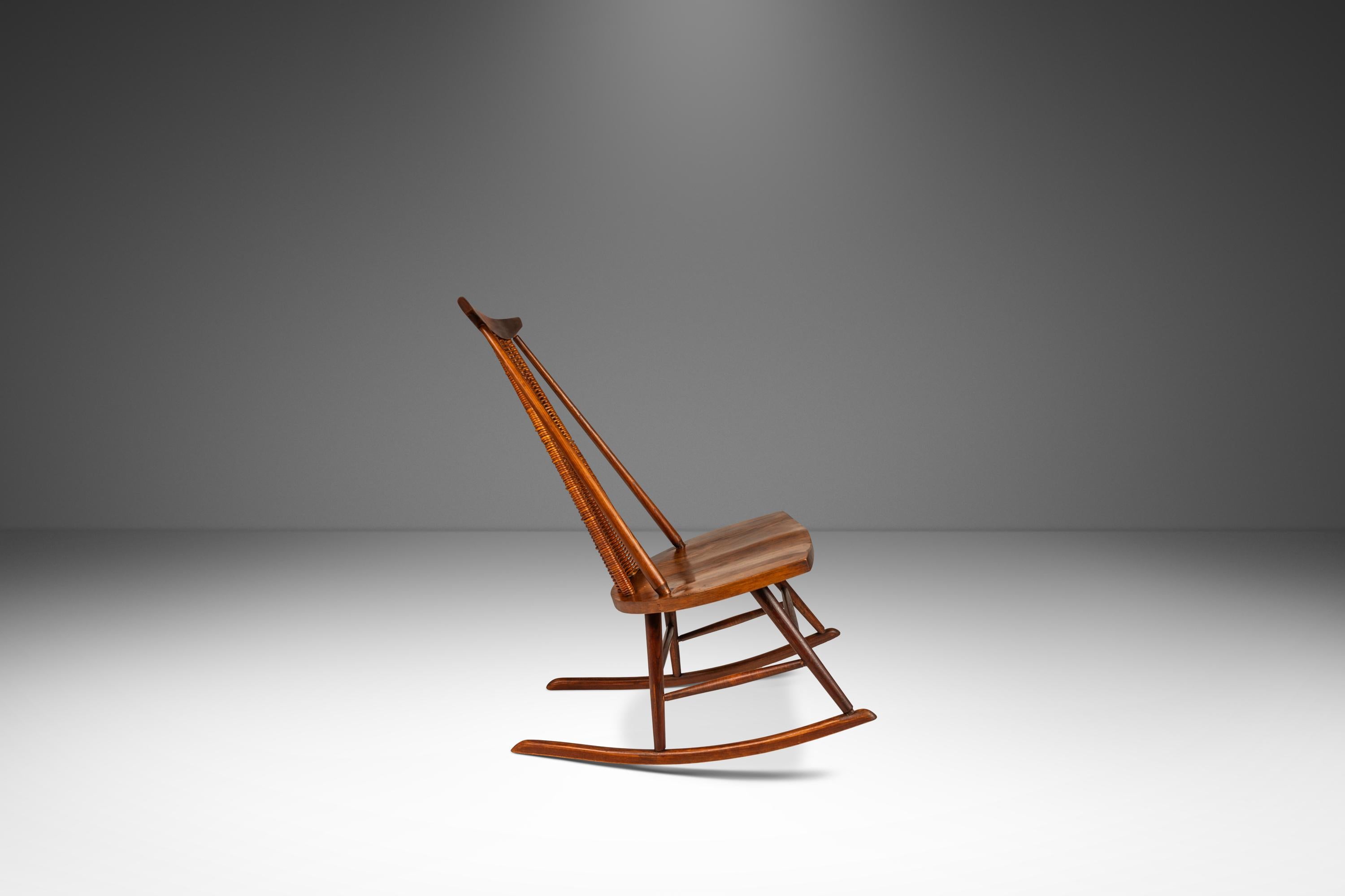Introducing a splendid Mid-Century Modern rocker designed by the incomparable Arthur Umanoff for Washington Woodcraft in the 1960s. Crafted from solid American black walnut and featuring a backrest of hand-woven rattan and sporting the perfect