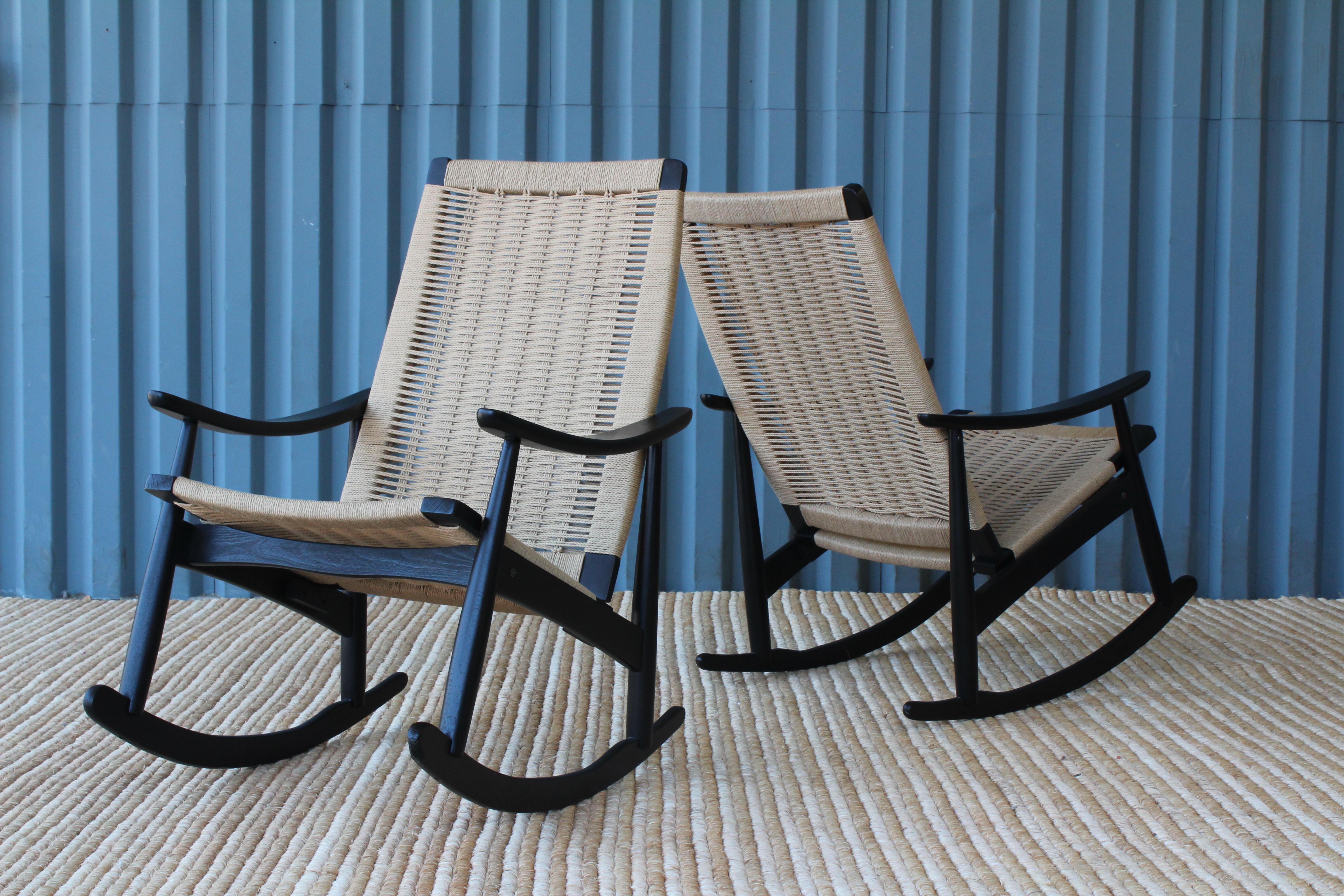 Pair of 1960s rocking chairs. The pair have been recently refinished in a satin black finish and feature new Danish cord seats. Sold individually, pair available.