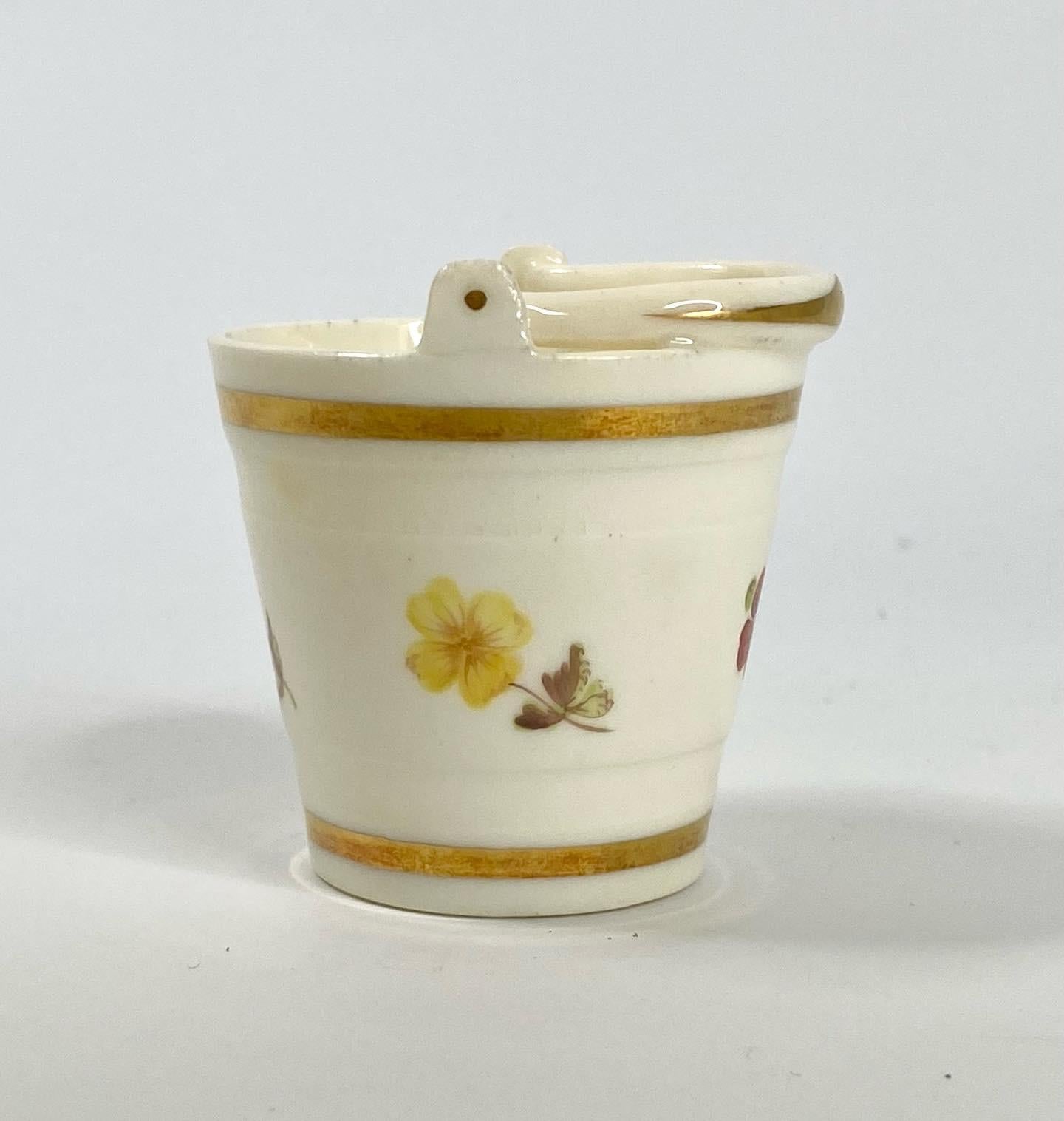 A rare Rockingham porcelain ‘Toy bucket’, 1826-1830. Modelled as a small, conical shaped bucket, with a lowered swing handle.
Hand painted to the body with flowers, between gilt bands, and gilt decoration to the handle.
Printed factory mark, and