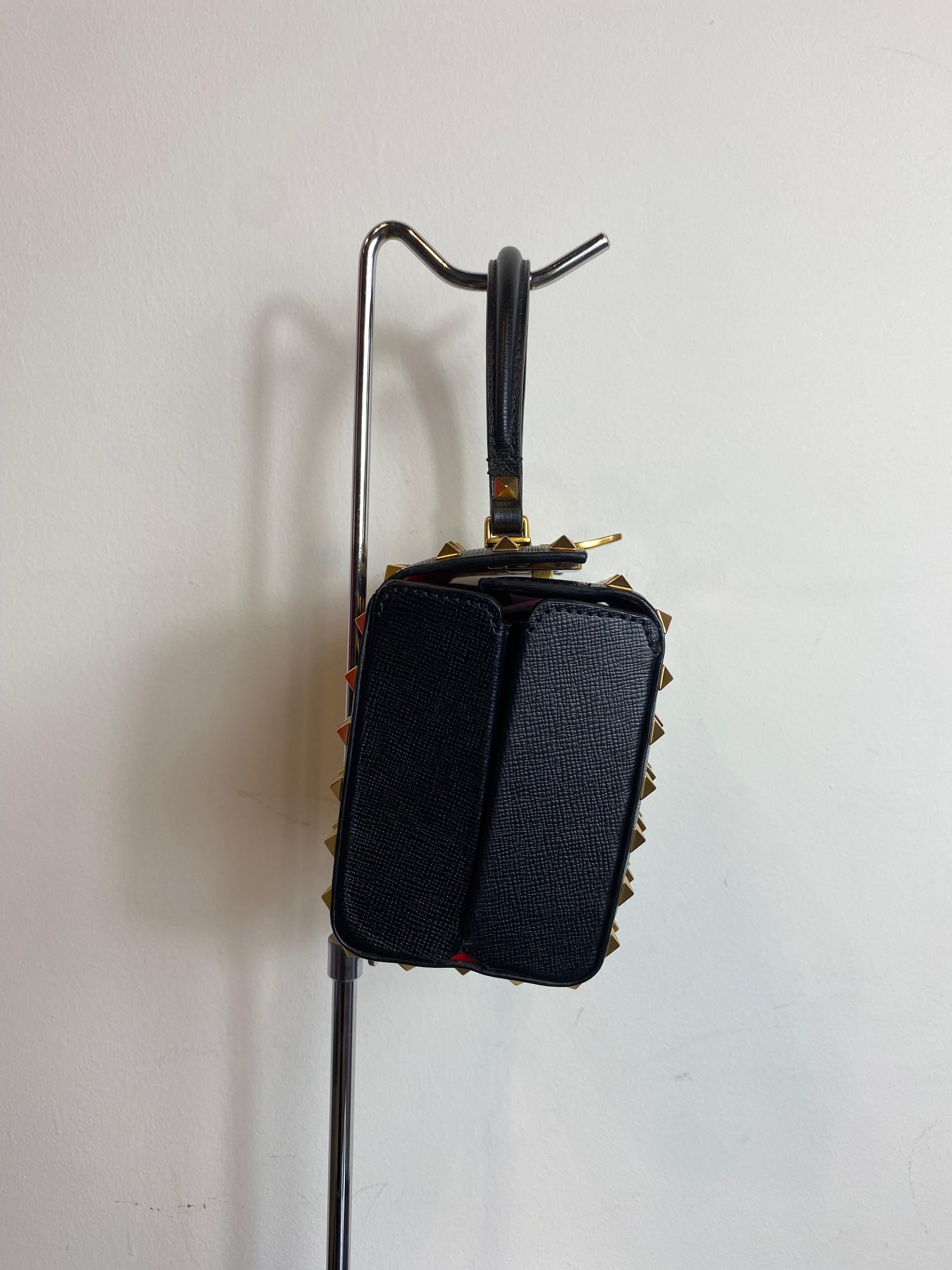 Valentino Rockstud alcove box bag, in black leather with studs and gold metal details. 
Hand but with adjustable and detachable shoulder strap. 
Red interior with pocket and card holder. 
In very good condition and with tag. 
With dust

Width