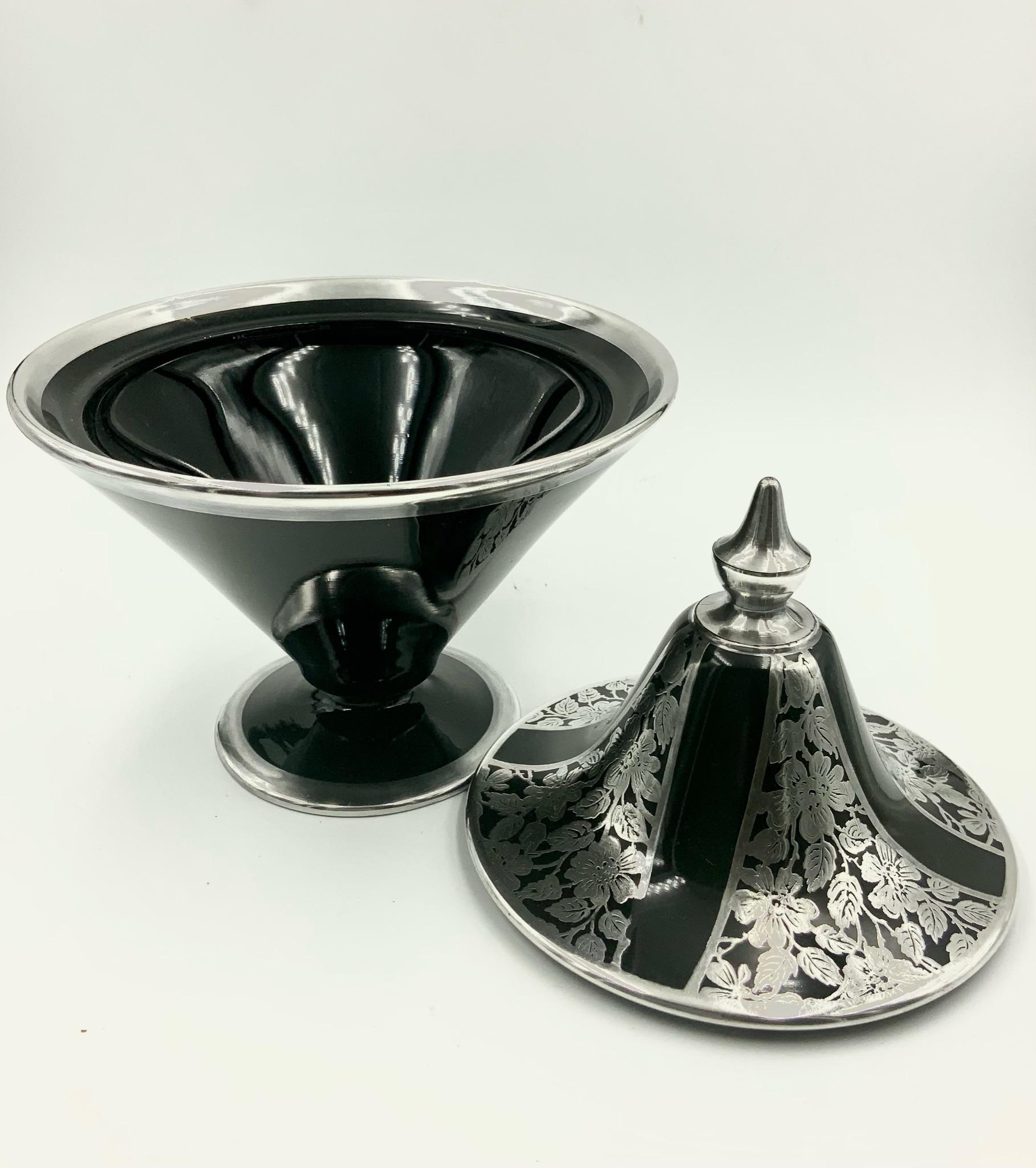 Simply elegant Art Deco covered candy dish / jar / box featuring four panels of flowers and leaves silver overlay design divided by a simple wide black line. The top is deco style pointy handle. There are silver rims at the base, on the top of the