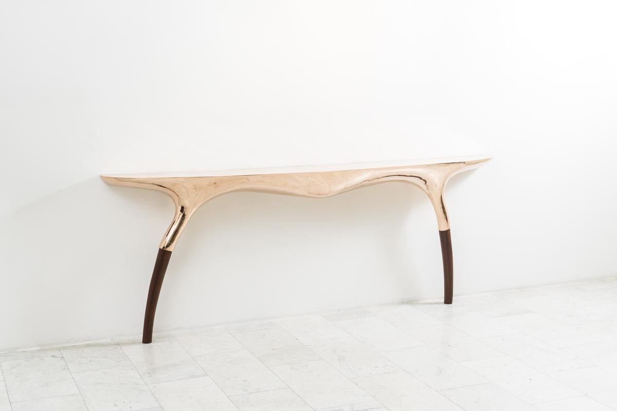 Alex Roskin’s Roco Console reflects modernist and primitivist influences.

The console’s sculpted shape resembles an anatomical form. The top, cast in bronze, is polished to a mirror finish. The base of the table, bowed and sinuous, fluidly extends