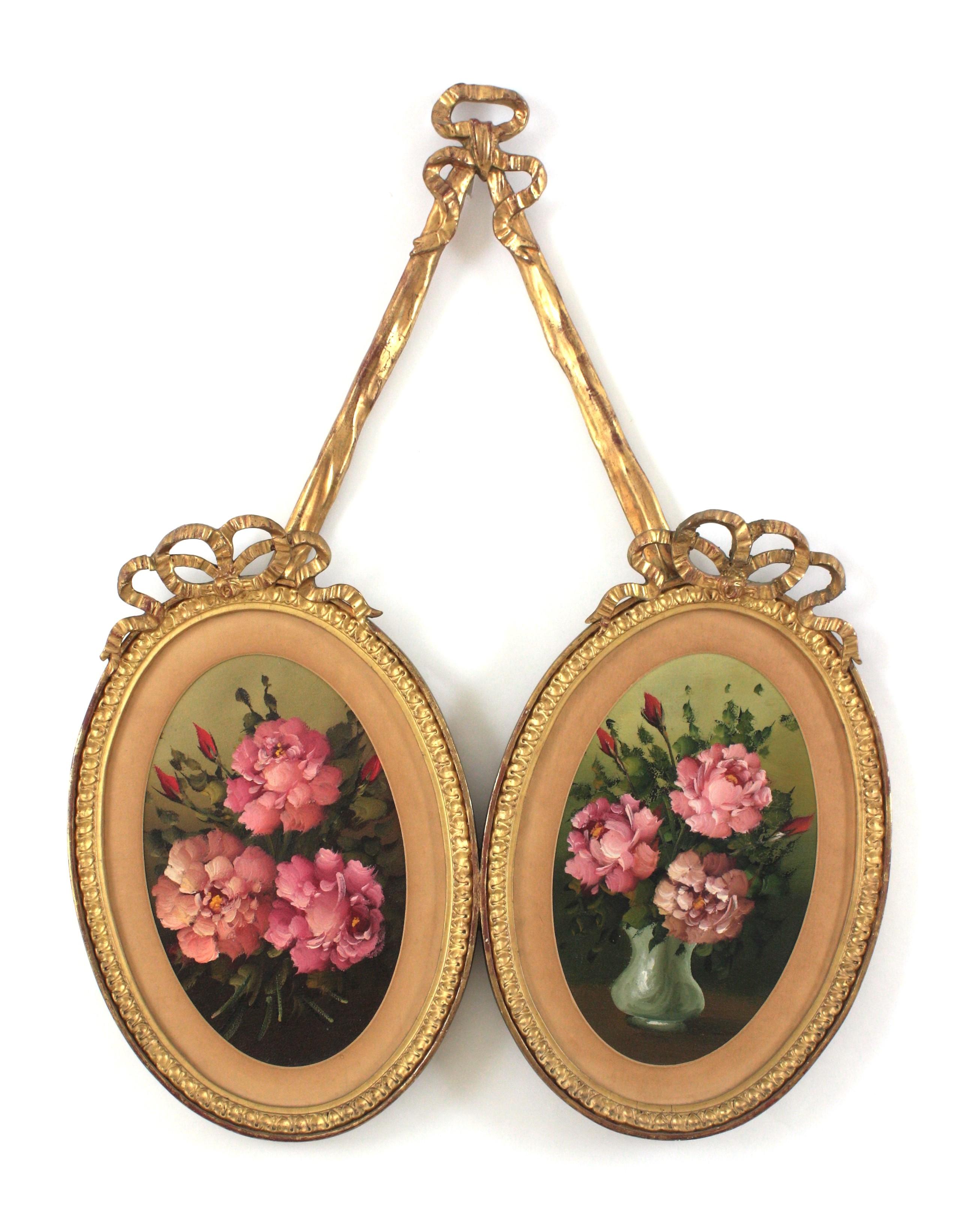Cadres en bois doré rococo espagnol avec peintures de fleurs 
Cadre de suspension ovale double en bois doré avec peinture de fleurs roses et ruban à nœud Détails.
Espagne, années 1940.
Ces superbes peintures à l'huile sur toile de forme ovale sont