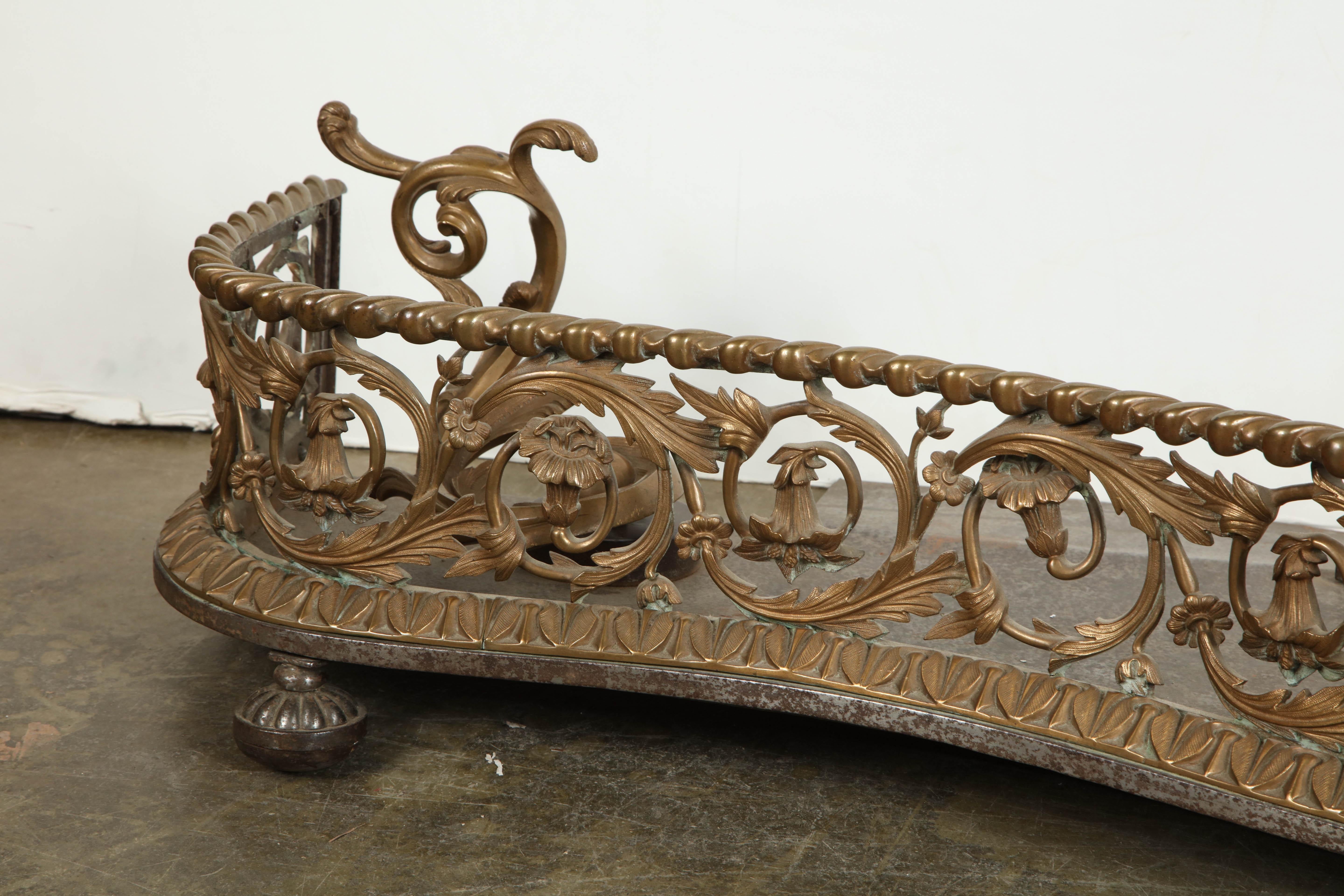 A fine English Rococo bronze openwork serpentine form fireplace fender.