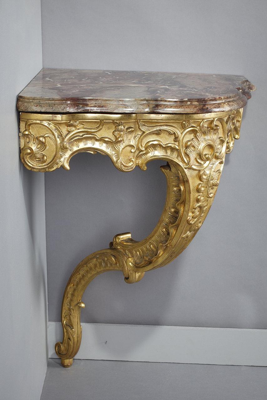Rocaille style corner console in carved and gilded wood, with rich decoration of foliage and volutes on a lozenge background. The design of the foot and the belt alternates curves and counter-curves that give this console a characteristic Rococo