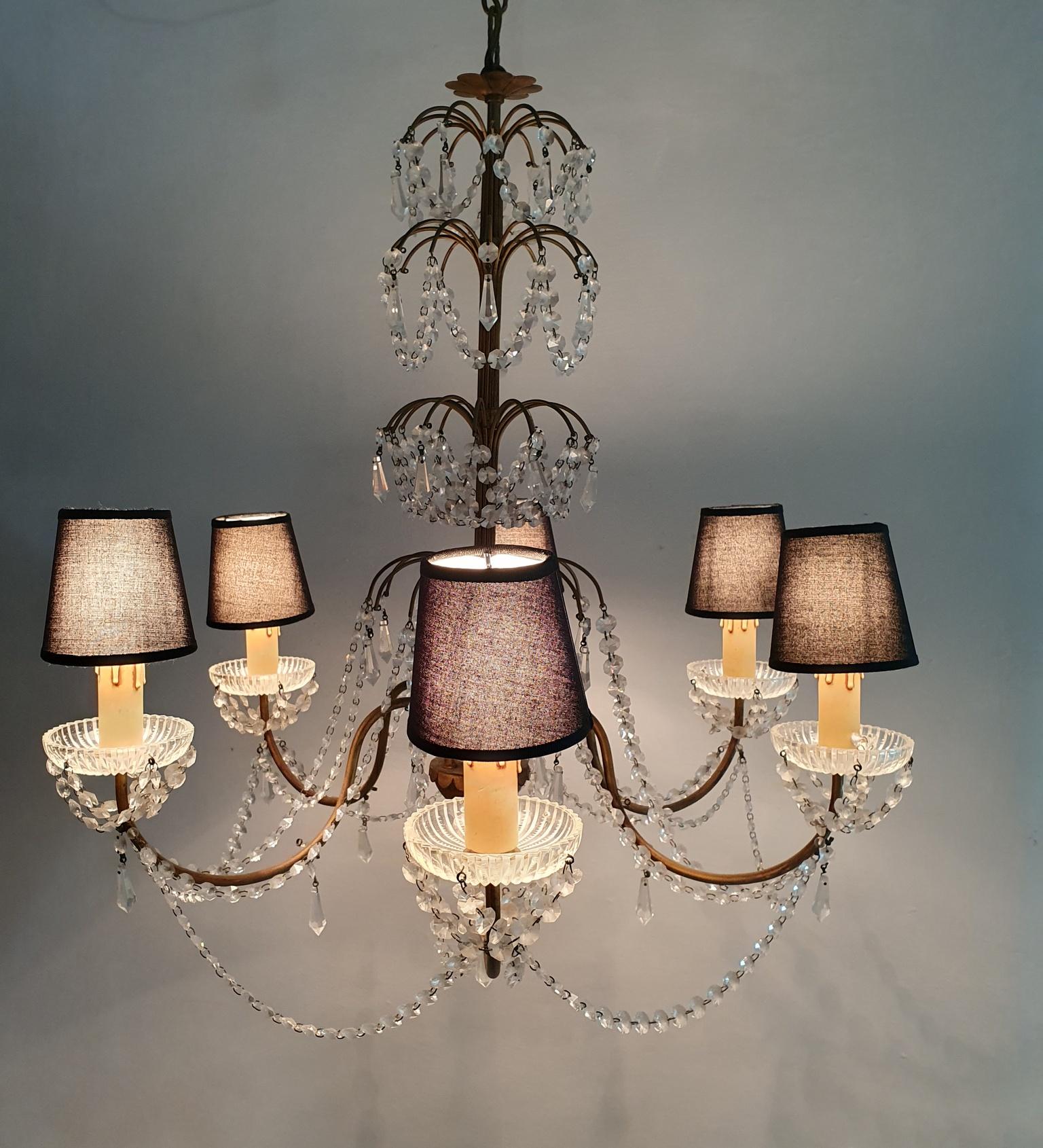 This beautiful chandelier boasts a Florentine Rococo style and is handmade in Florence, Italy circa 1950. The gilded iron frame is adorned with an array of crystals, which exude a soft and delicate glow when illuminated. This timeless design is a