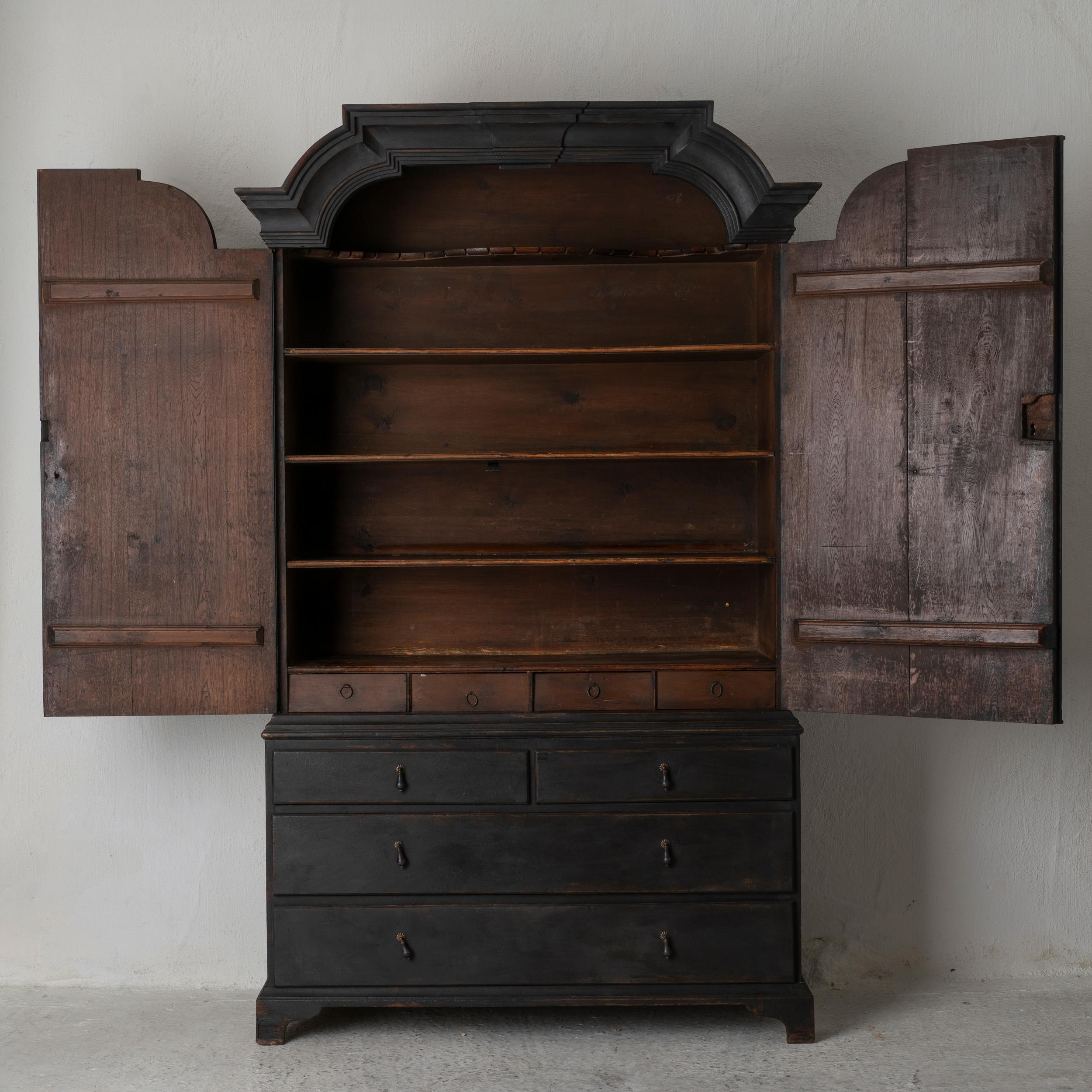 Un mobile da pranzo realizzato nel XVIII secolo e nel periodo rococò in Svezia. Corona a due pezzi, ad arco. Realizzato in legno di quercia e successivamente dipinto in nero Laserow. Intarsi a forma di stella sulle porte. Due cassetti più grandi e