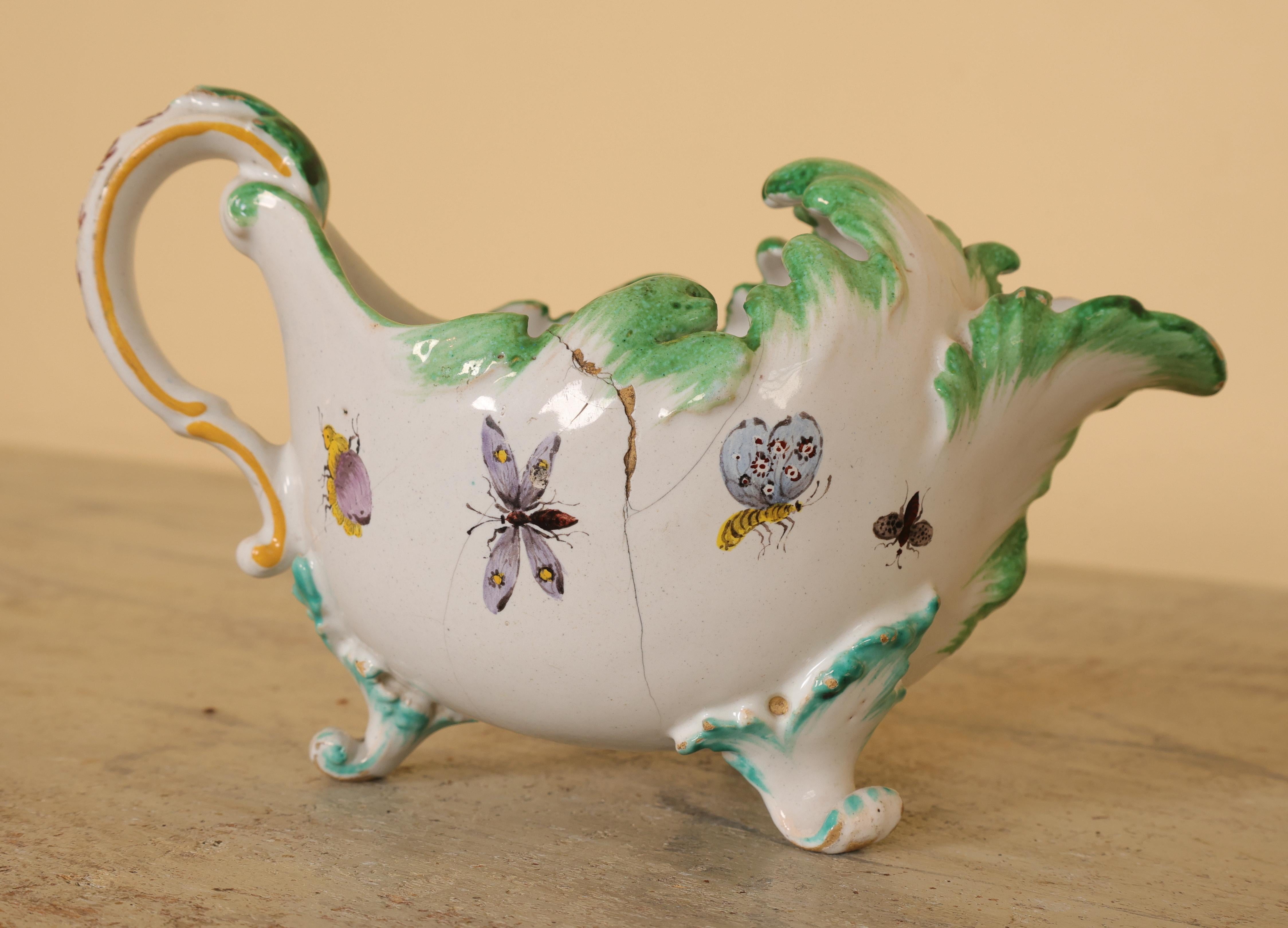 Jarra de crema rococó de loza, fabricada en la fábrica sueca de loza Rörstrand. La jarra está pintada en colores policromos, con bellos detalles de insectos. Su elegante diseño muestra el estilo rococó plenamente desarrollado. Hay una grieta en un