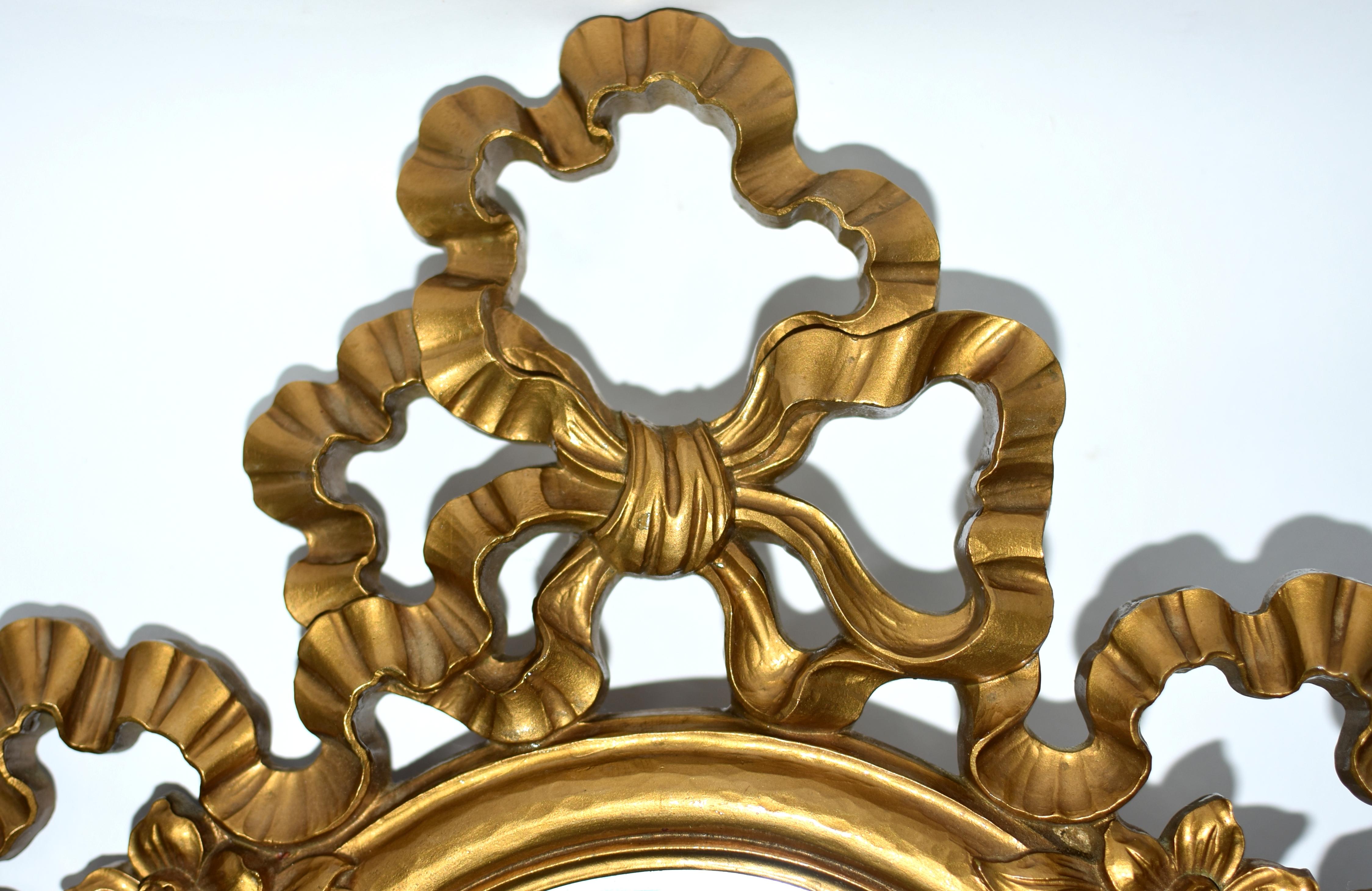 Un bellissimo specchio da parete vintage in ottime condizioni. Con un elaborato stile rococò caratterizzato da delicati fiocchi, fiori e nappe. Il timbro indica Made in USA della società Syroco. 