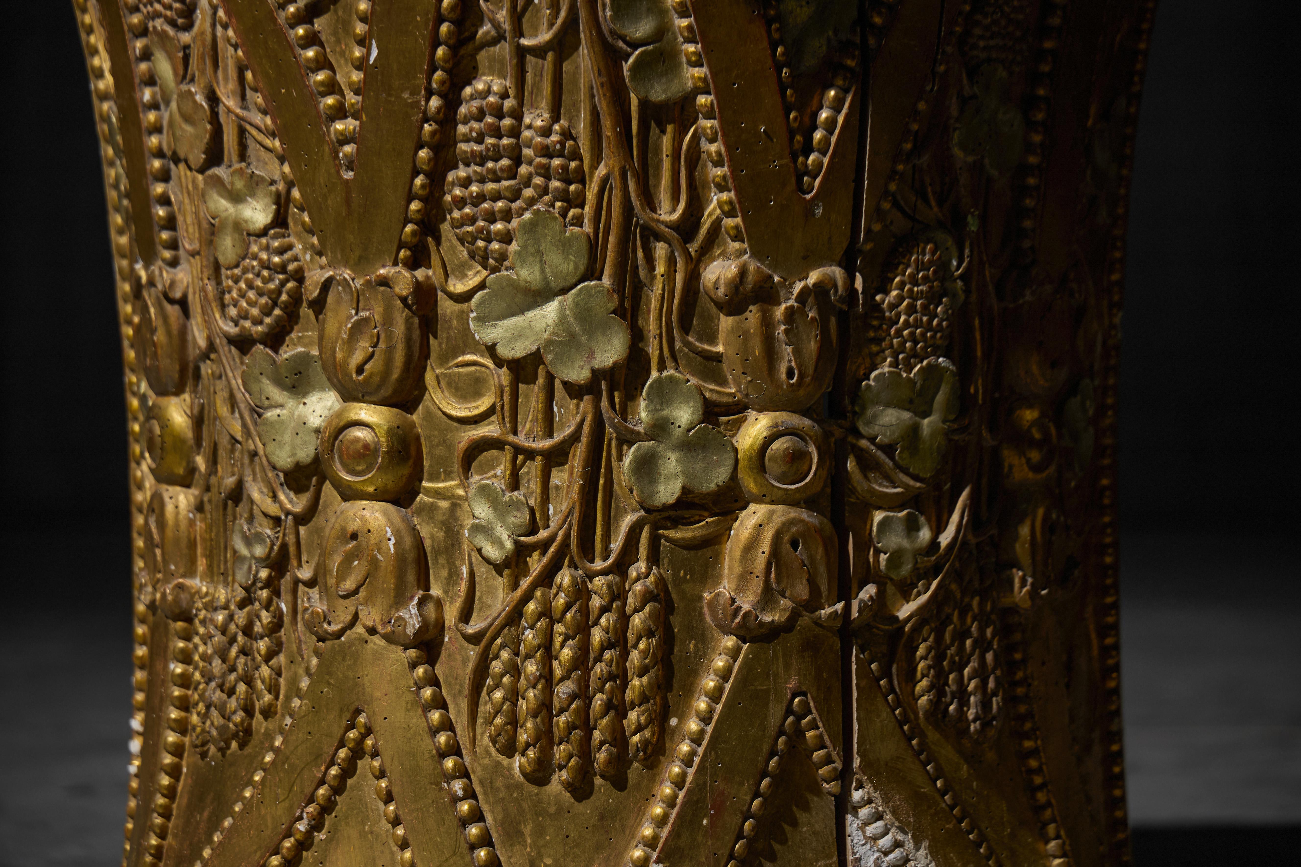 A highly decorative Italian Rococo giltwood demilune console, likely dating to the 18th century, featuring a dramatic flared form and intricate hand-carved ornamentation. The surface is richly adorned with motifs of grapes, wheat, pomegranates, and