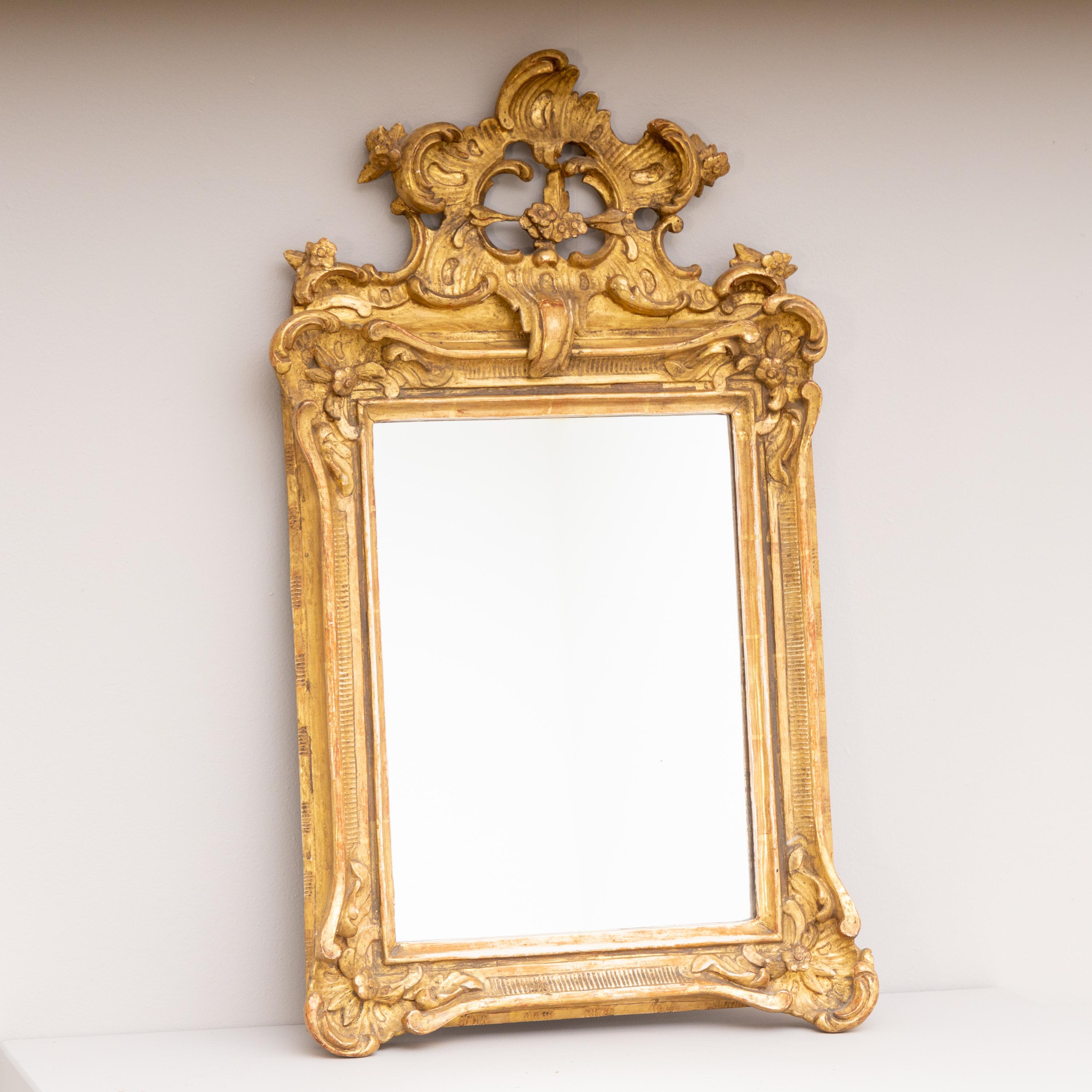 Small wall mirror with asymmetrical rocaille decoration and gold patinated frame.
