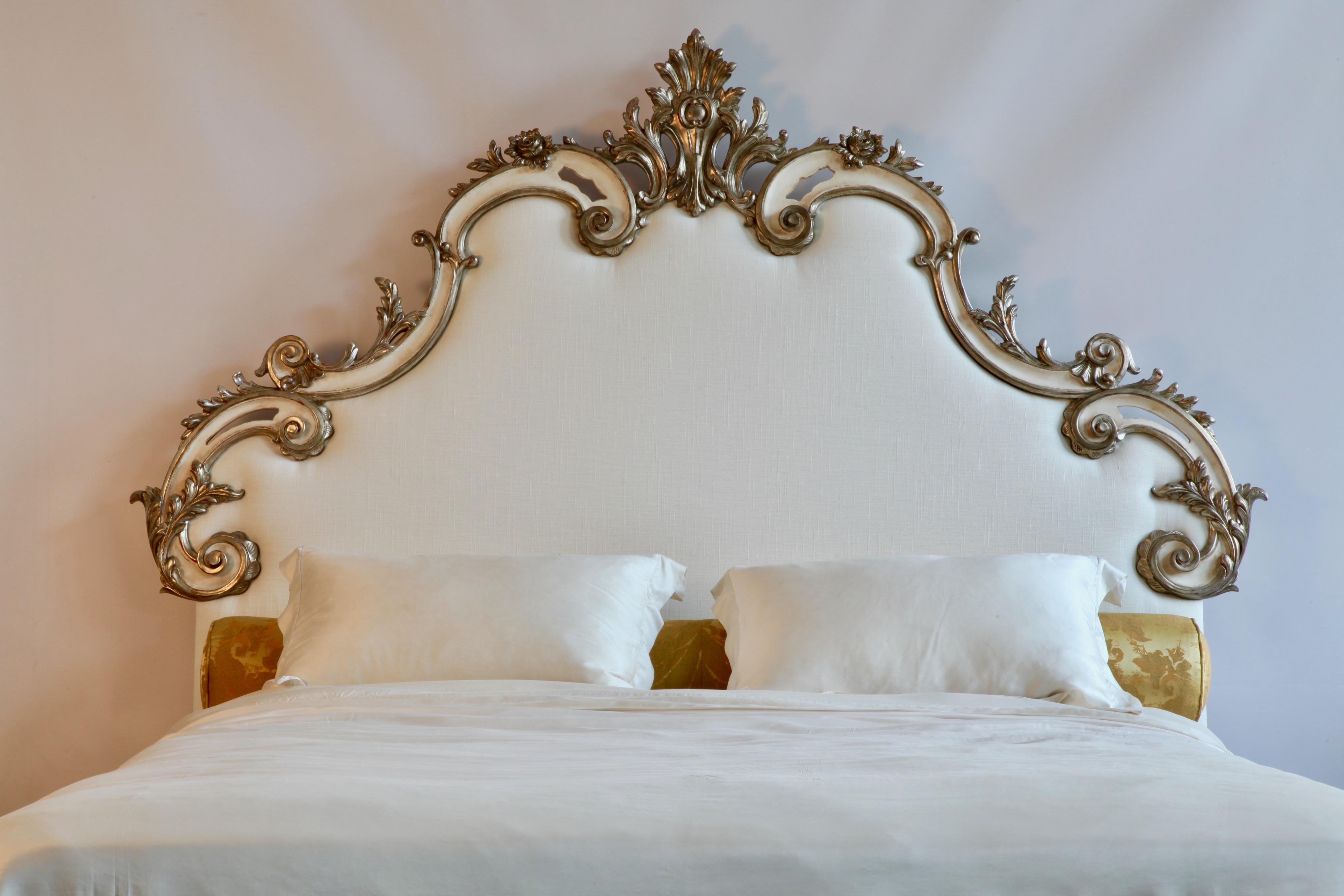 Hand carved Rococo headboard finished in an old, taupe, white patina, enhanced by hand gilded, silver highlights. The carving consists of sweeping, deep scrolled, 's' curves and decoratively carved accents of the stylised acanthus leaf.