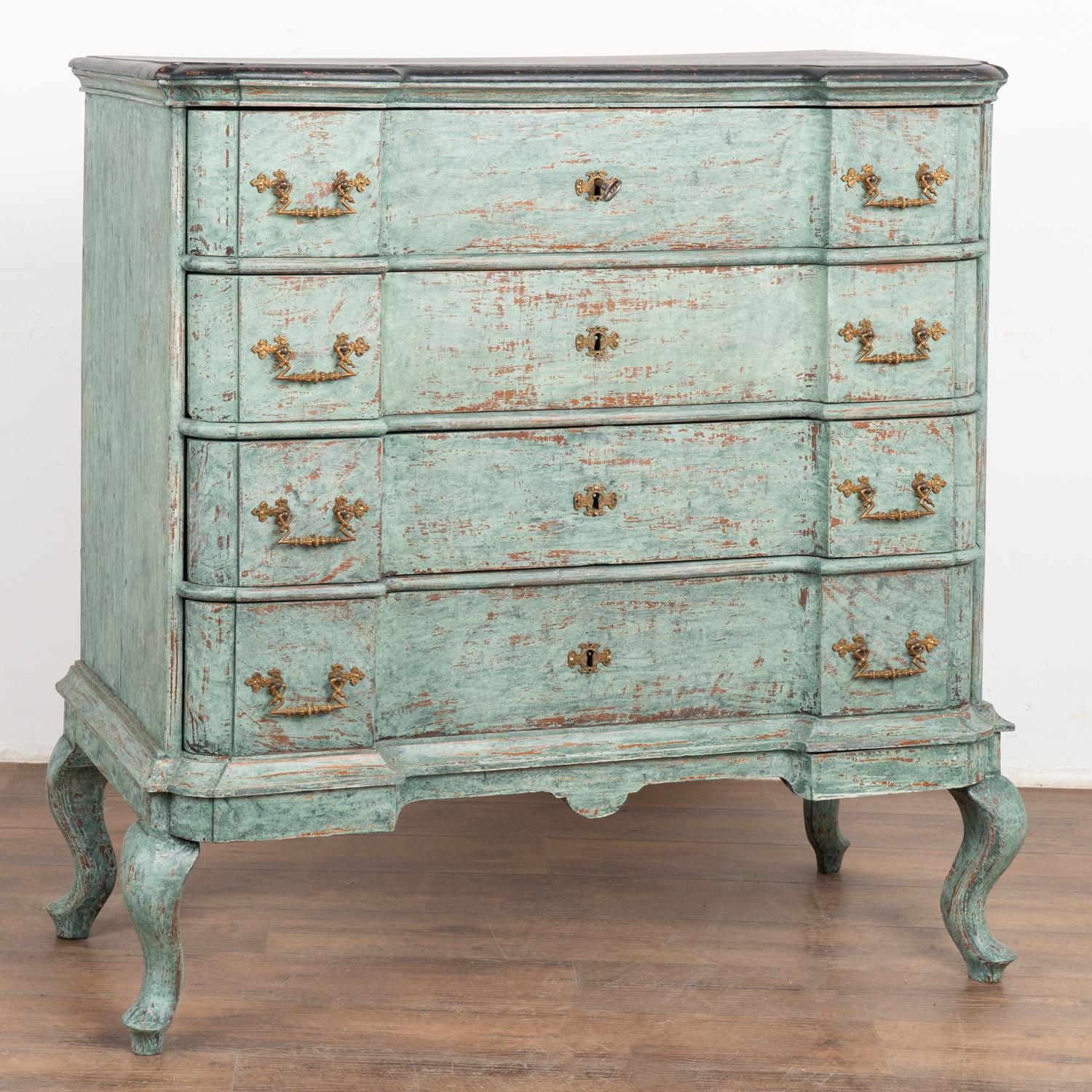 Large antique oak rococo chest of four drawers with handsome brass hardware pulls all resting on cabriolet feet.
This commode has been given an exceptional new professional blue/green seafoam layered painted finish and has been lightly distressed,