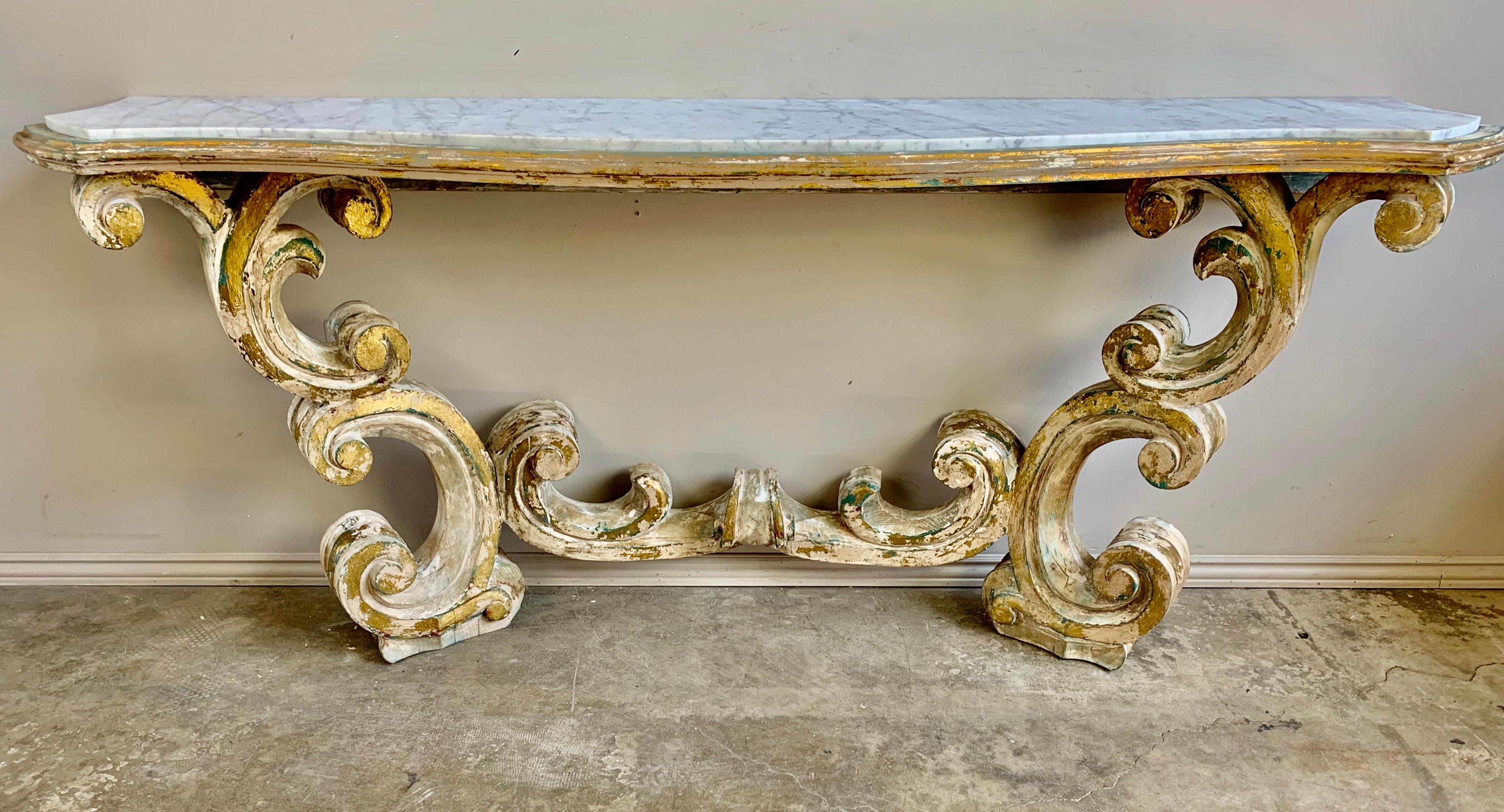 Rococo style painted and parcel gilt console with inset Carrara marble top. Beautiful scrolled swirling acanthus leaves make up this elegant piece. We actually have a pair of these if needed.