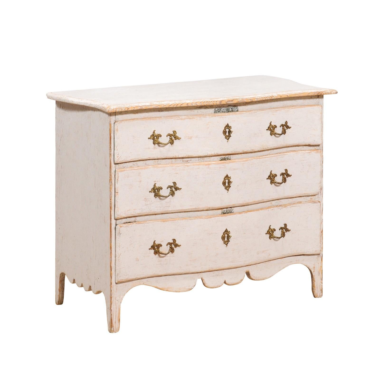 A Swedish Rococo period three-drawer commode from circa 1770 with light gray cream painted finish, carved skirt and serpentine front. This Swedish Rococo period three-drawer commode, dating back to circa 1770, is a magnificent example of the opulent