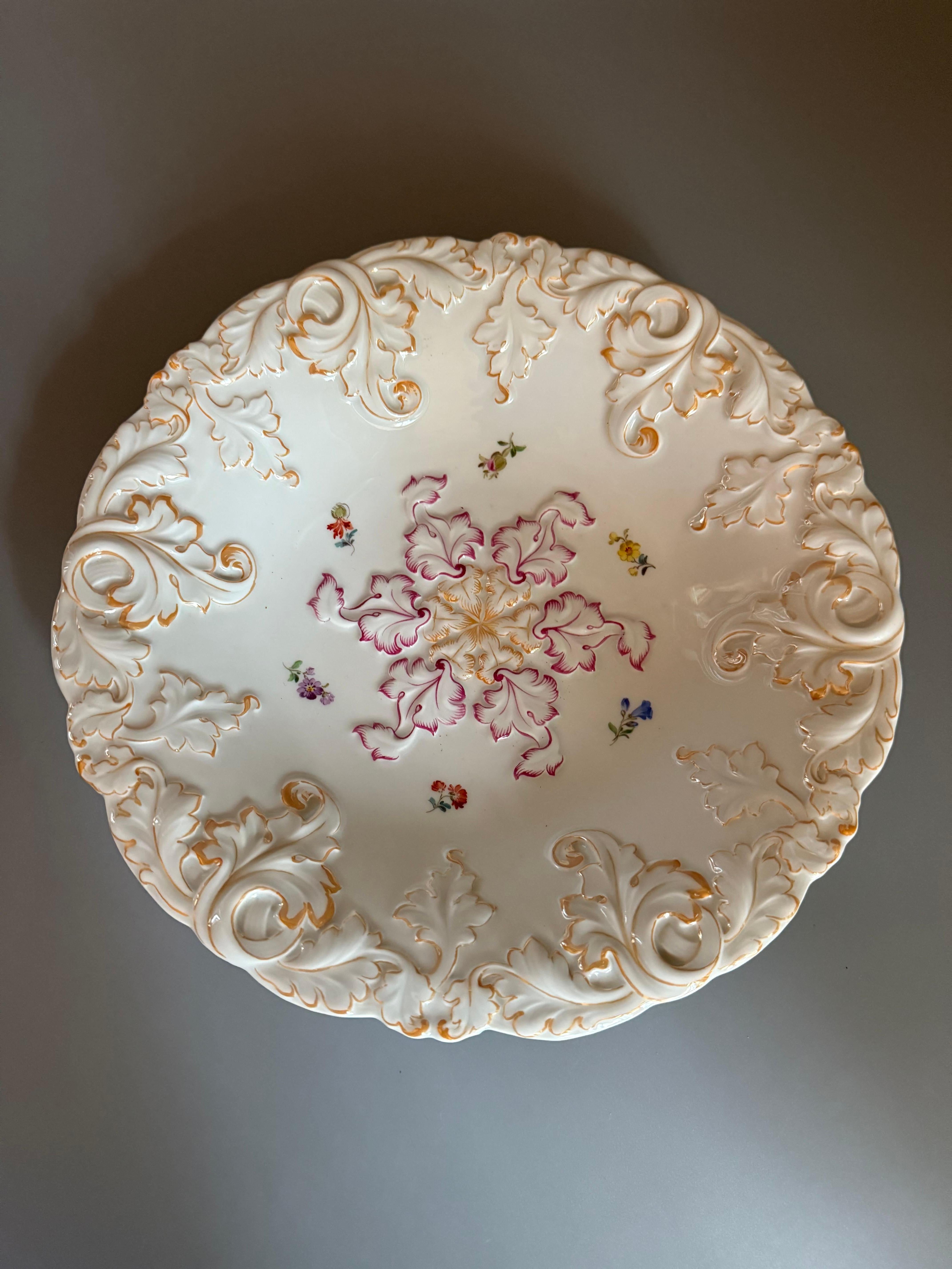 Es handelt sich um eine Schale aus Meissener Porzellan, wahrscheinlich eine Kompott- oder Servierschale, die sich durch ihr erhabenes Reliefdekor im Rokoko-Stil und handgemalte Blumenmotive auszeichnet. 
Herkunft: Das aus Deutschland stammende