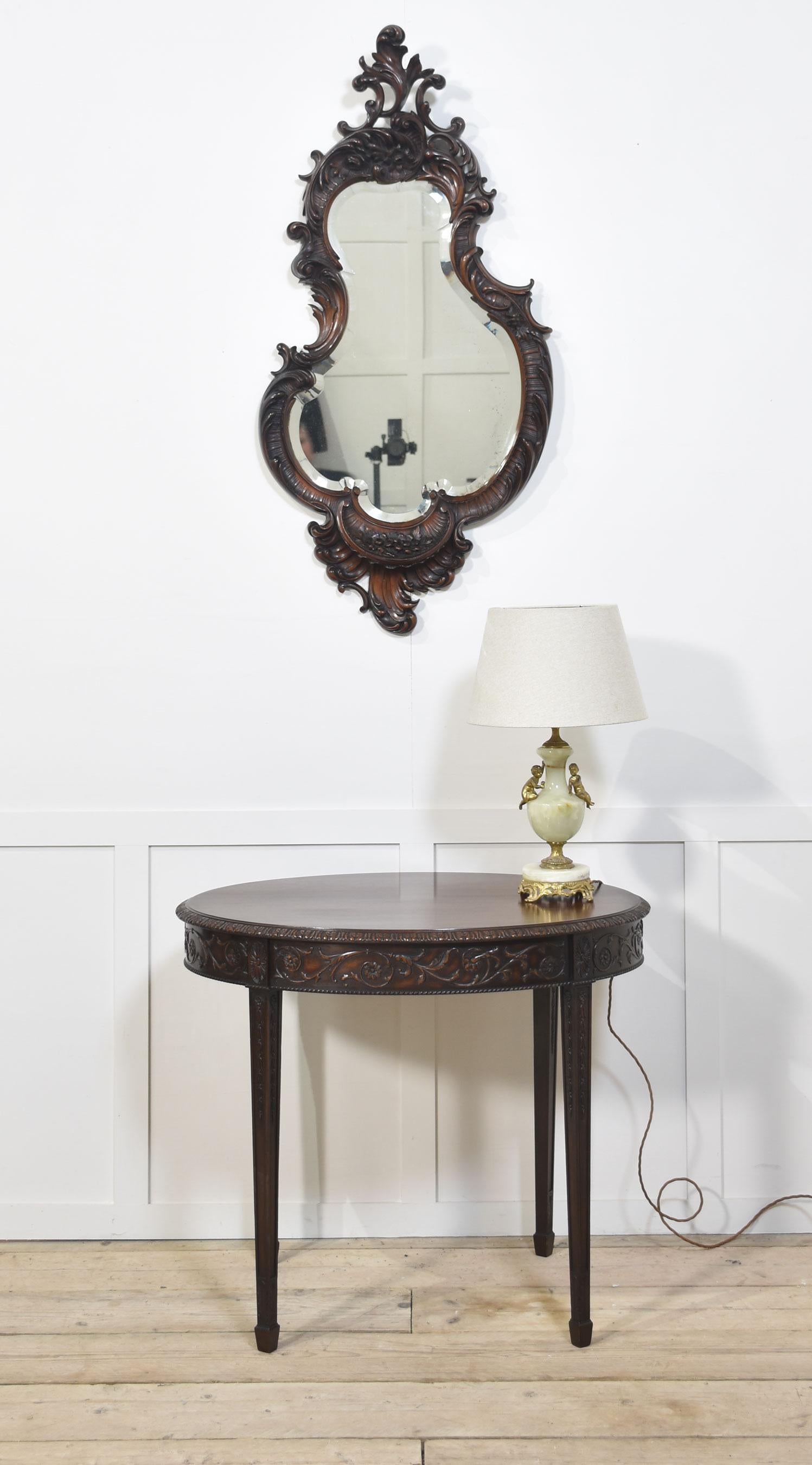 19th century Rococo Revival mahogany wall mirror, the asymmetrical shape with a beveled glass plate, heavily carved with rocaille scrolls and foliate details.
Dimensions
Height 49 Inches
Width 23 Inches
Depth 6.5 Inches