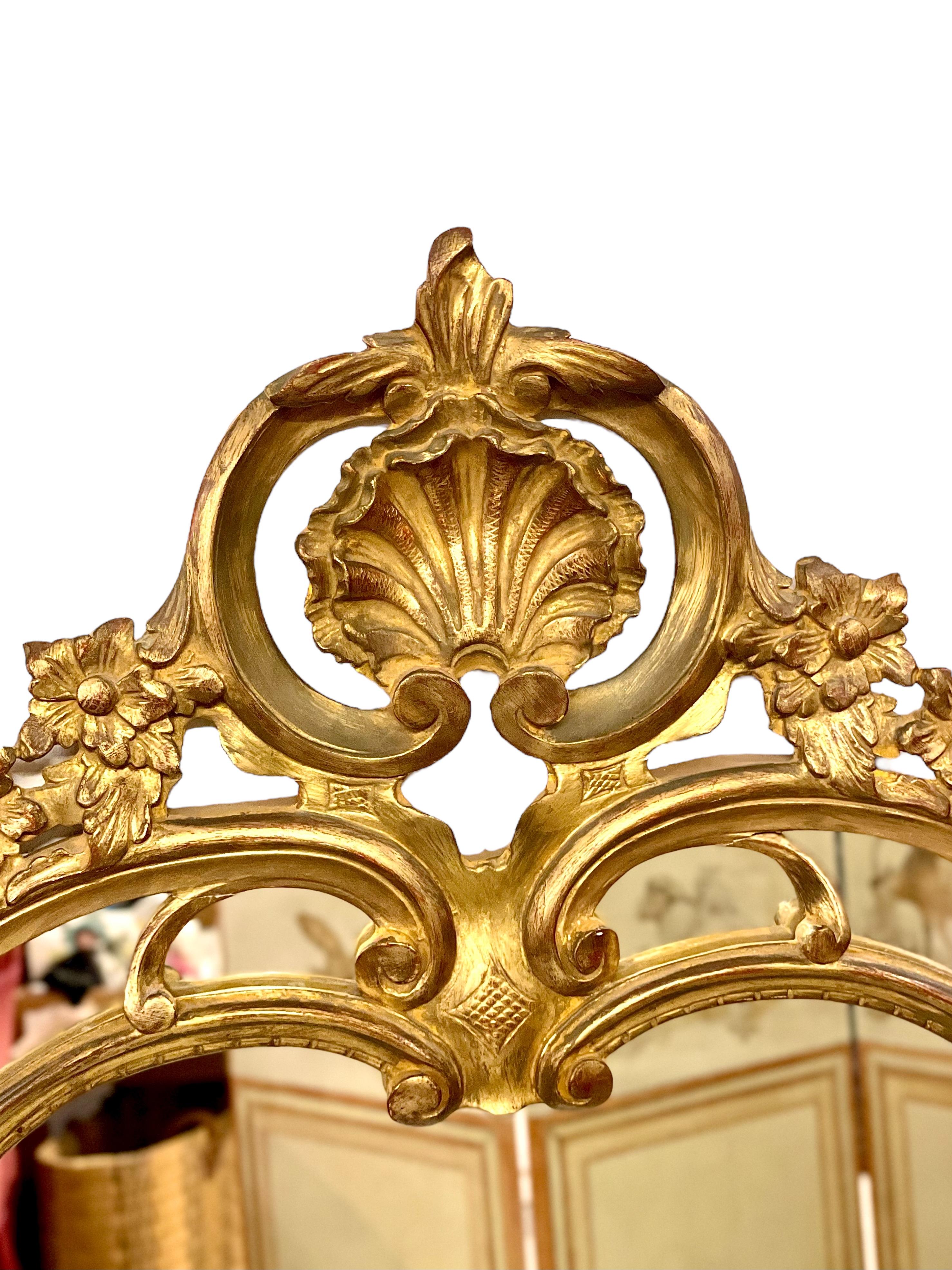 This exquisite gilded mirror is a stunning example of Rococo-inspired craftsmanship, standing 115 cm tall and radiating timeless elegance. The frame features intricate hand-carved details, including floral motifs, scrolls, and a central shell crest